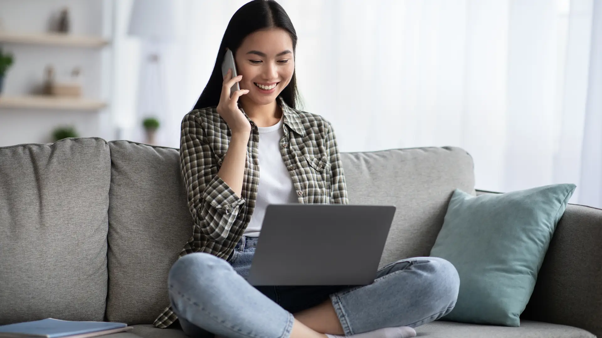 Una chica desde el sofá de su casa llamando por teléfono a la aseguradora Clinicim Una chica desde el sofá de su casa llamando por teléfono a la aseguradora Clinicim
