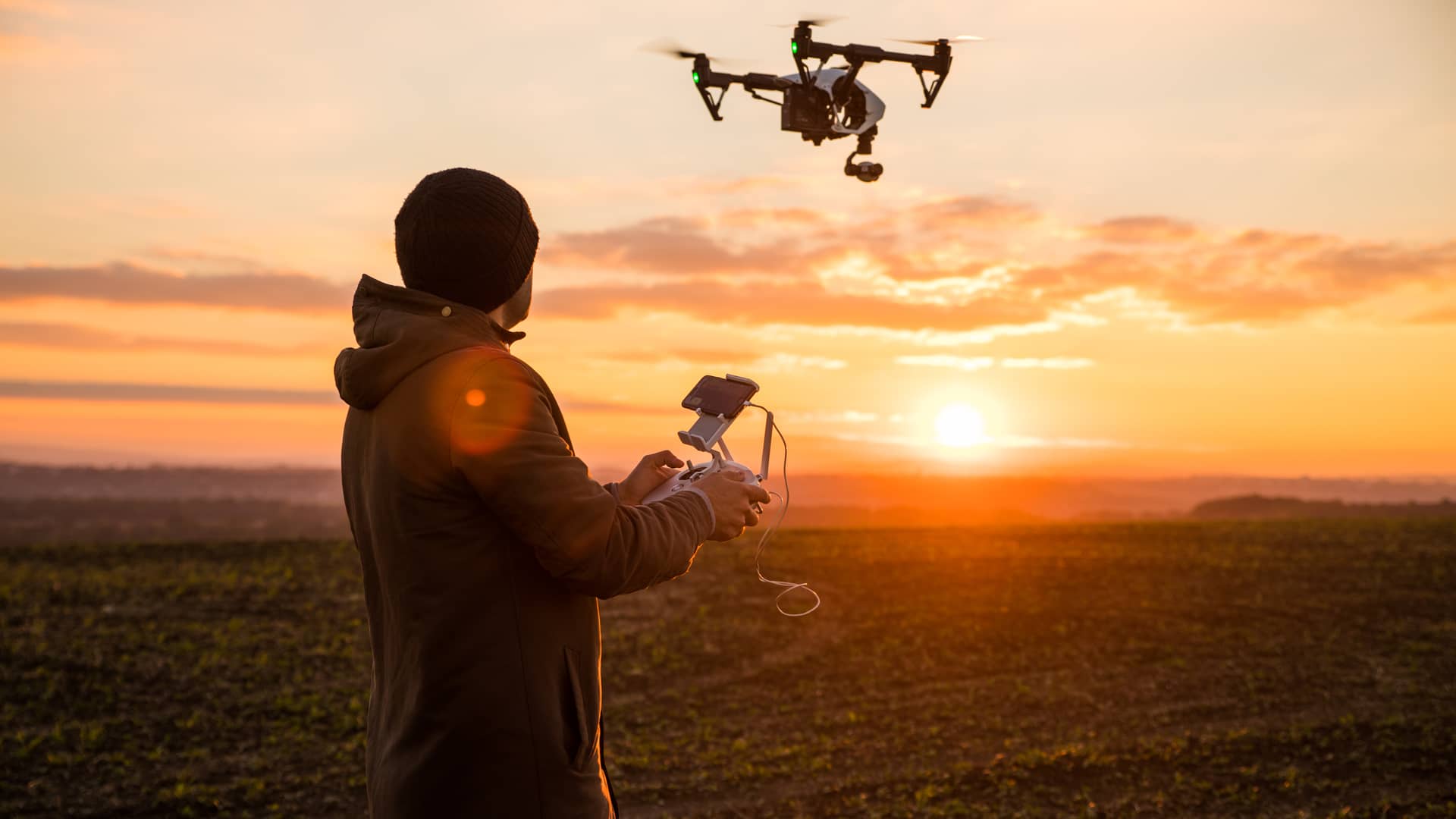 un joven en el campo disfrutando mientras vuela su dron con el seguro de generali