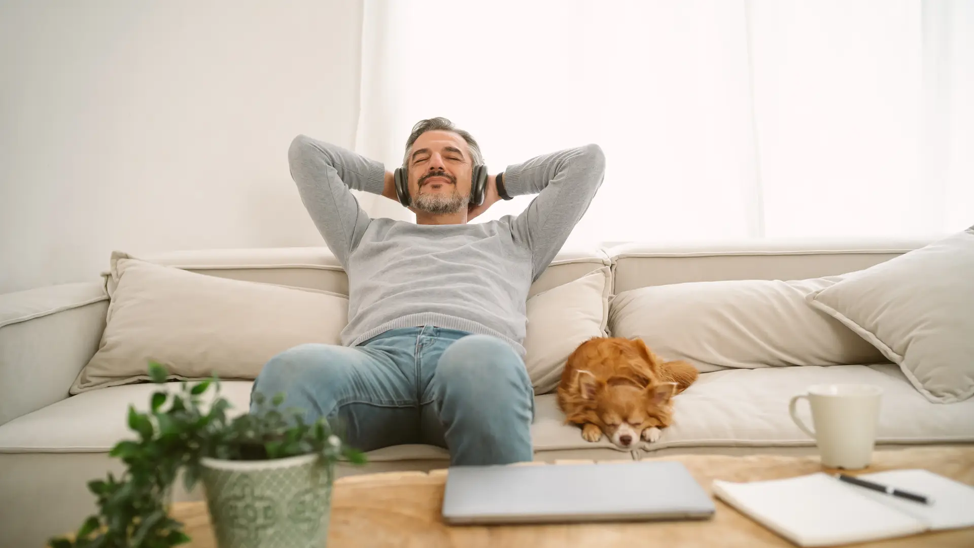 Un hombre disfrutando en el sofá relajado porque tiene un seguro de hogar de Lagun Aro Un hombre disfrutando en el sofá relajado porque tiene un seguro de hogar de Lagun Aro