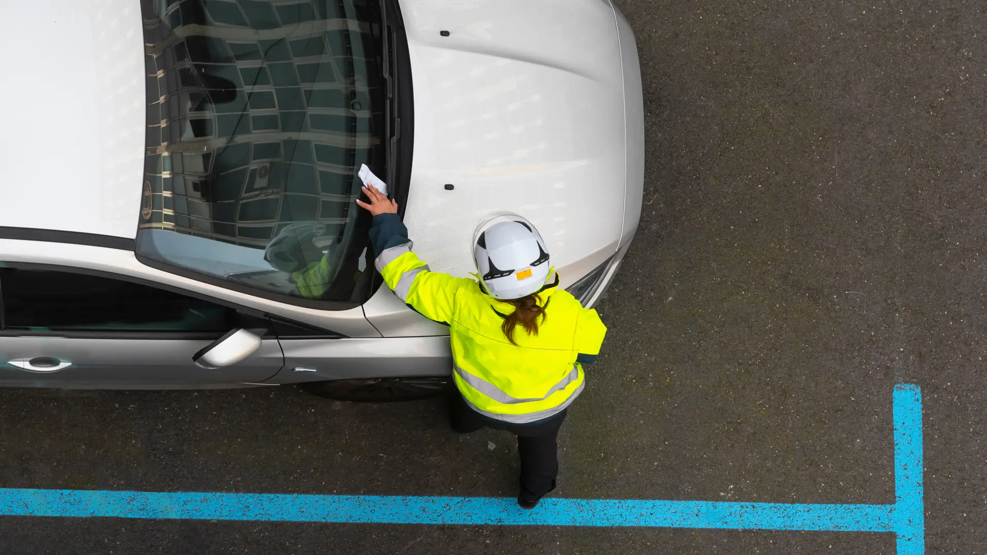 Agente de la policía colocando una multa de tráfico en el parabrisas del coche de un cliente de Mapfre Agente de la policía colocando una multa de tráfico en el parabrisas del coche de un cliente de Mapfre