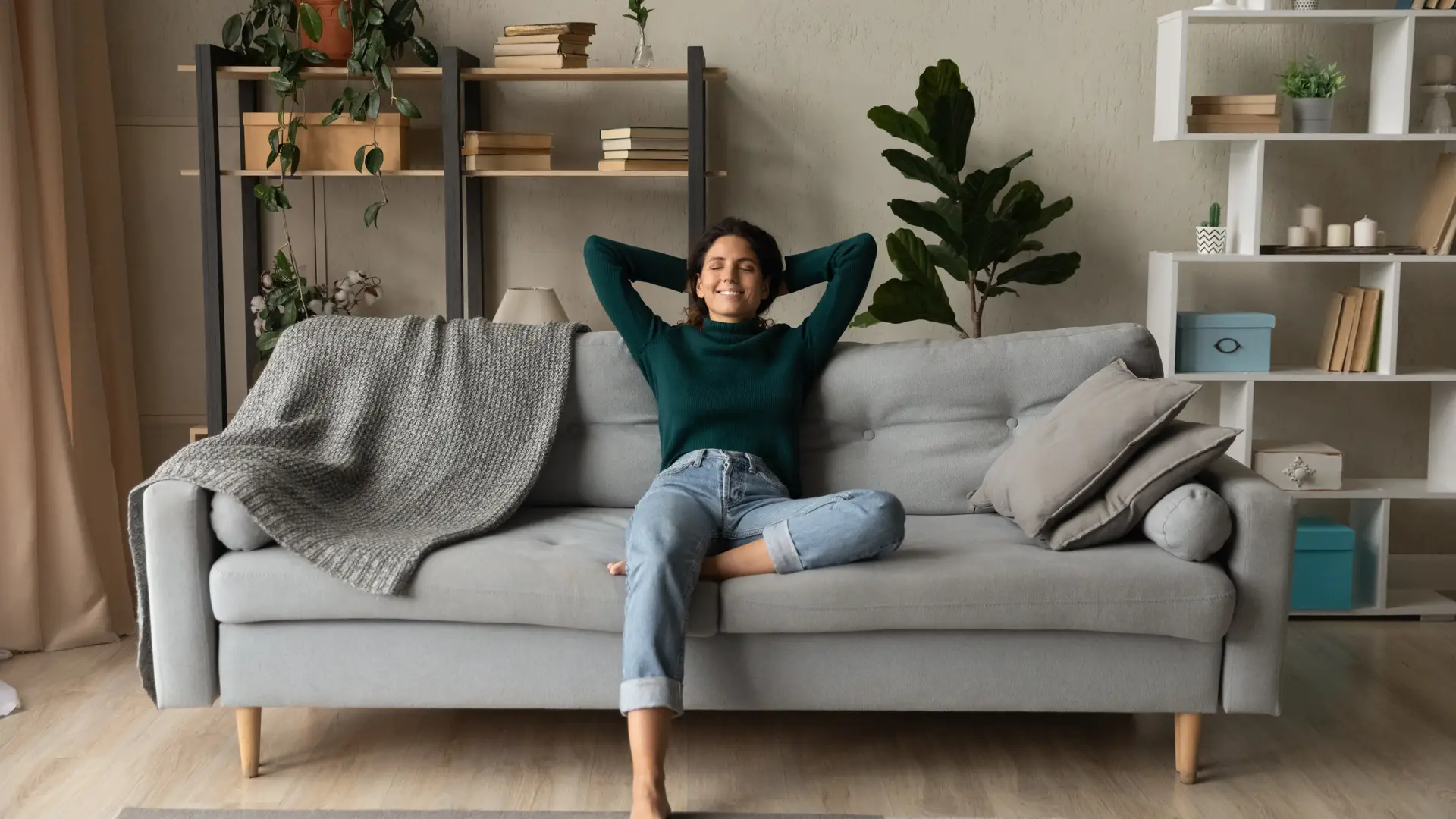 Una joven contenta sentada en el sofá muy tranquila porque tiene un seguro de hogar de MMT Seguros Una joven contenta sentada en el sofá muy tranquila porque tiene un seguro de hogar de MMT Seguros