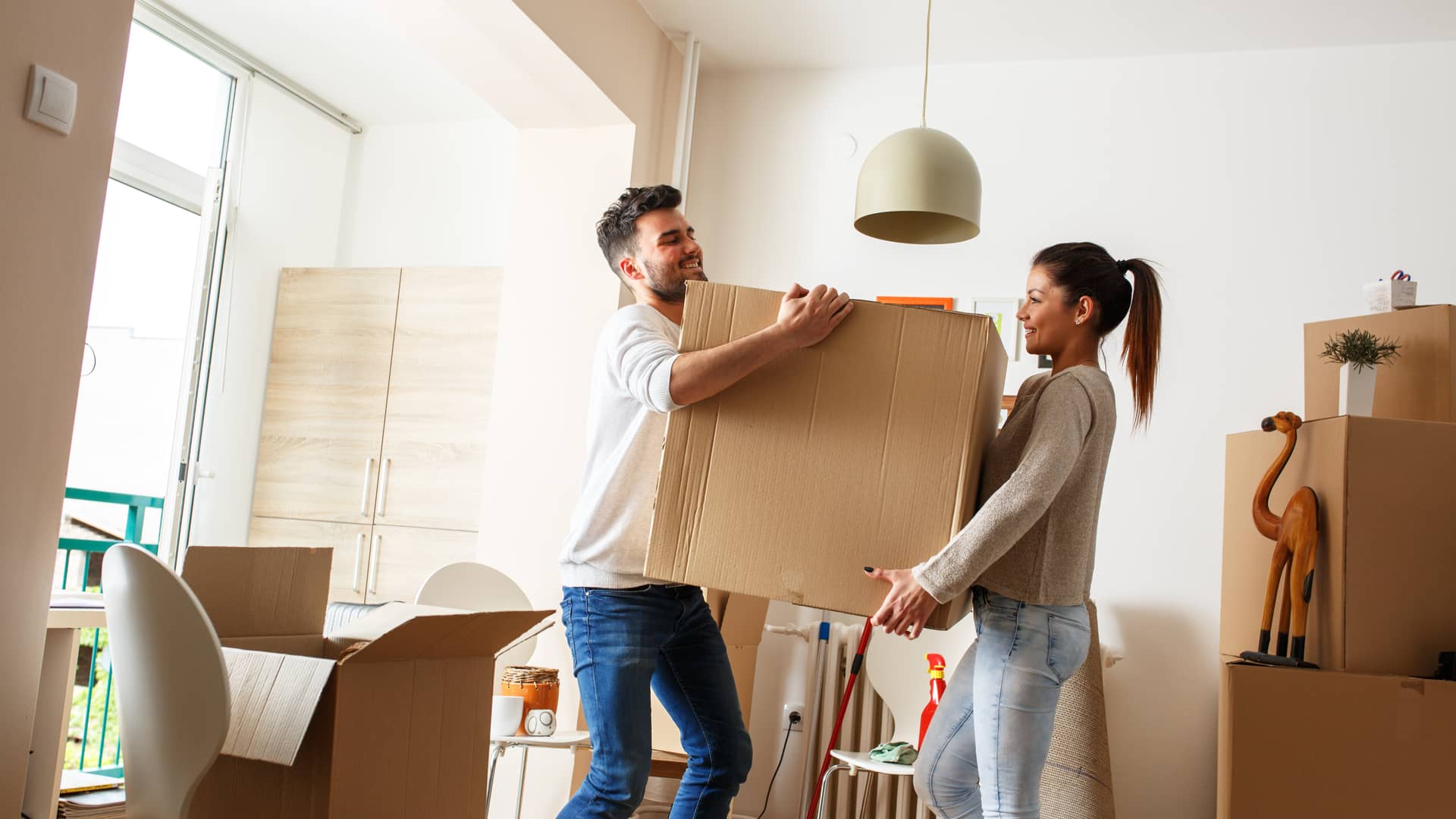 Una pareja joven ordenando las cajas de la mudanza a un piso donde el casero tiene contratado el seguro de hogar y de arrendamiento con la Mutua Madrileña Una pareja joven ordenando las cajas de la mudanza a un piso donde el casero tiene contratado el seguro de hogar y de arrendamiento con la Mutua Madrileña