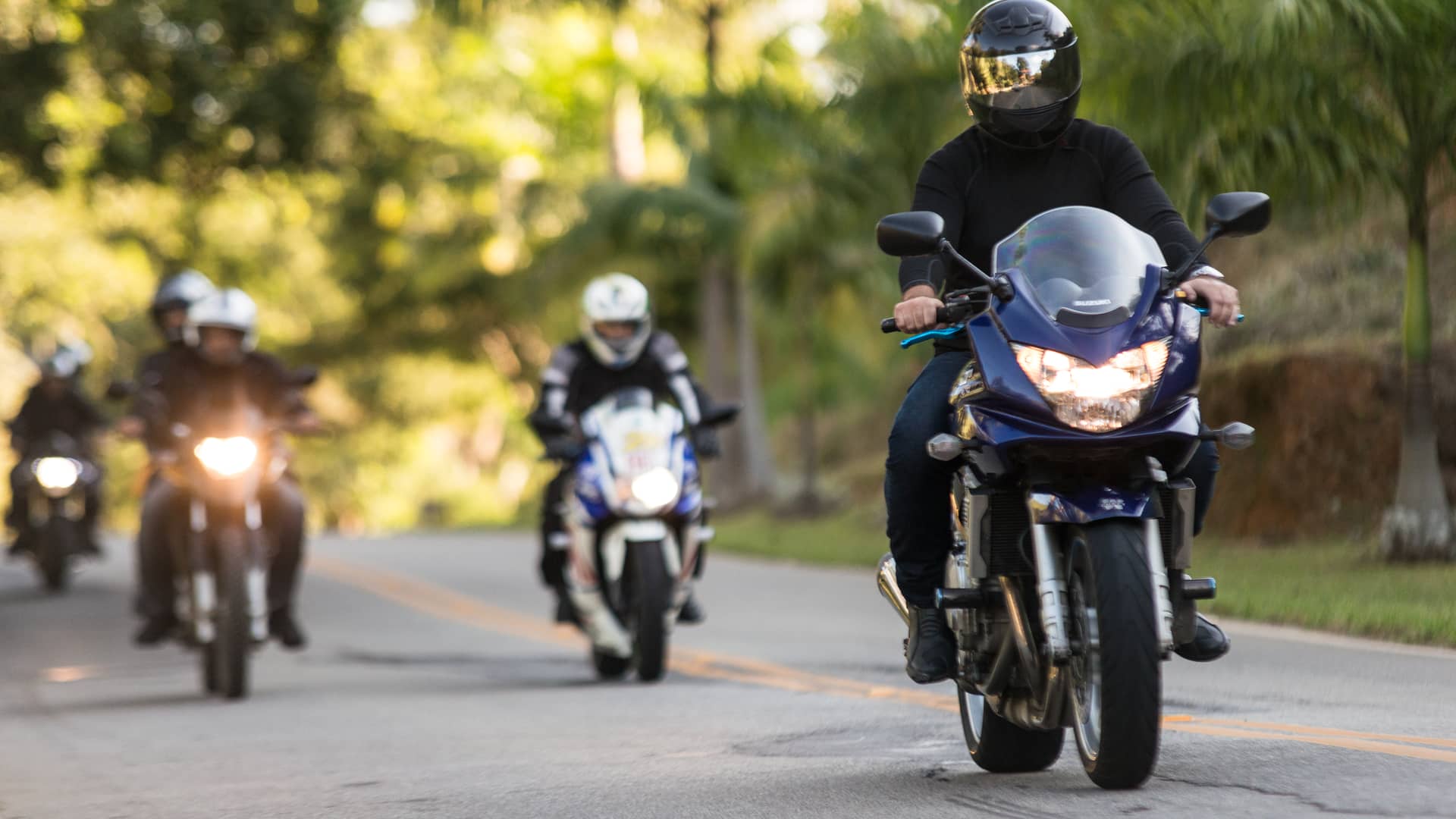 Joven a la cabeza conduciendo su moto asegurada con mutua madrileña acompañado de sus amigos