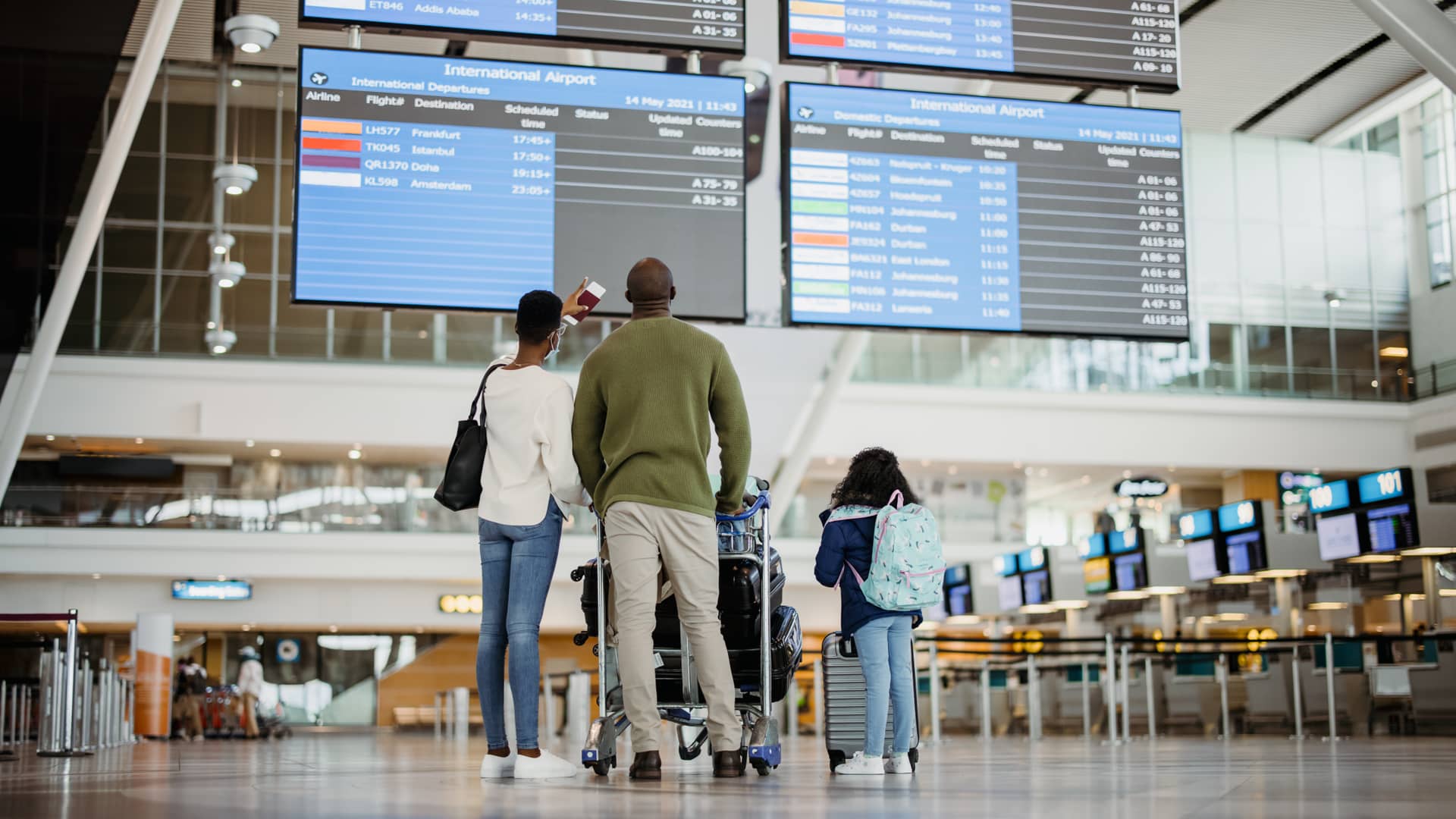 Una familia de espaldas en el aeropuerto que se va de vacaciones con su seguro de viajes de la Mutua Madrileña Una familia de espaldas en el aeropuerto que se va de vacaciones con su seguro de viajes de la Mutua Madrileña