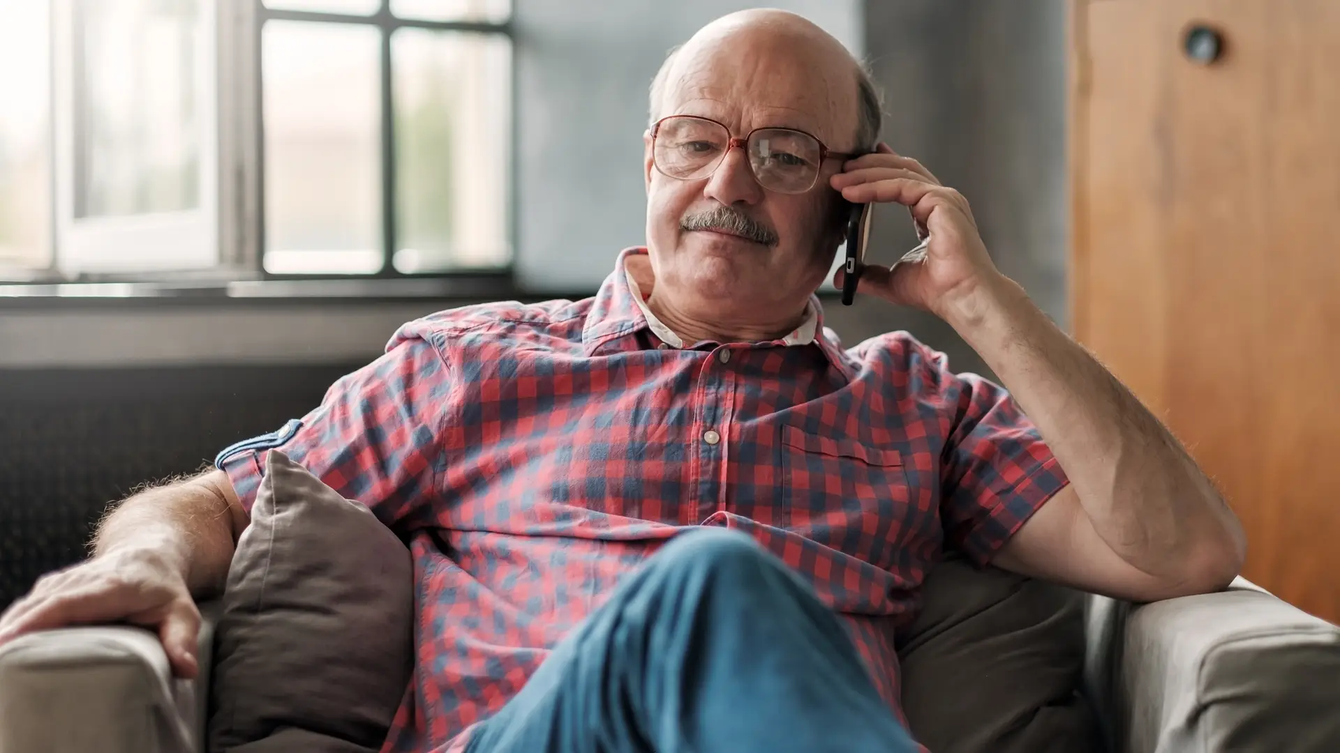 Hombre en un sillóon de casa hablando por teléfono con su aseguradora Norte Hispana