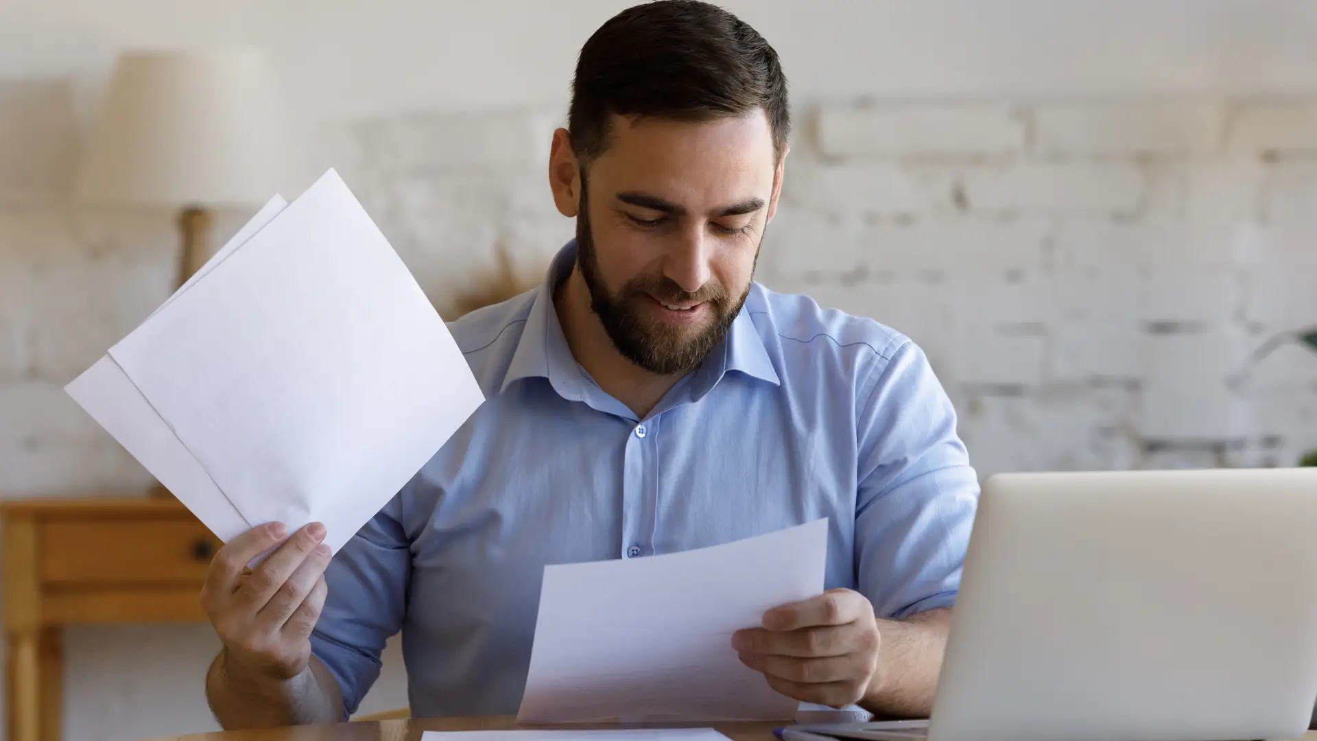 chico joven contento leyendi los papeles que le indican los descuentos de sus seguros con ocaso