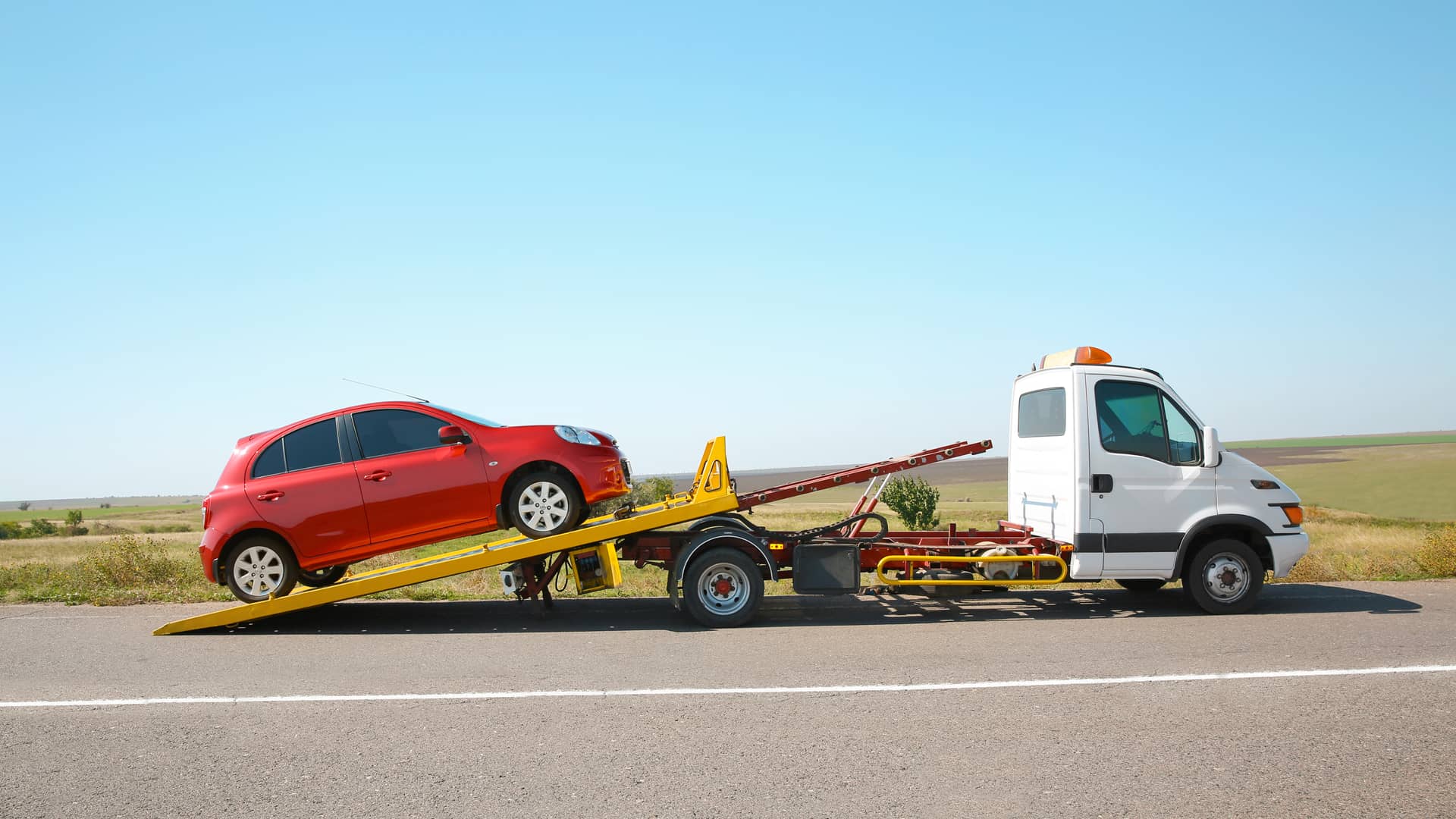 Una grua montando un coche en la carretera que representa el asistencia de la aseguradora Qualitas Auto Una grua montando un coche en la carretera que representa el asistencia de la aseguradora Qualitas Auto