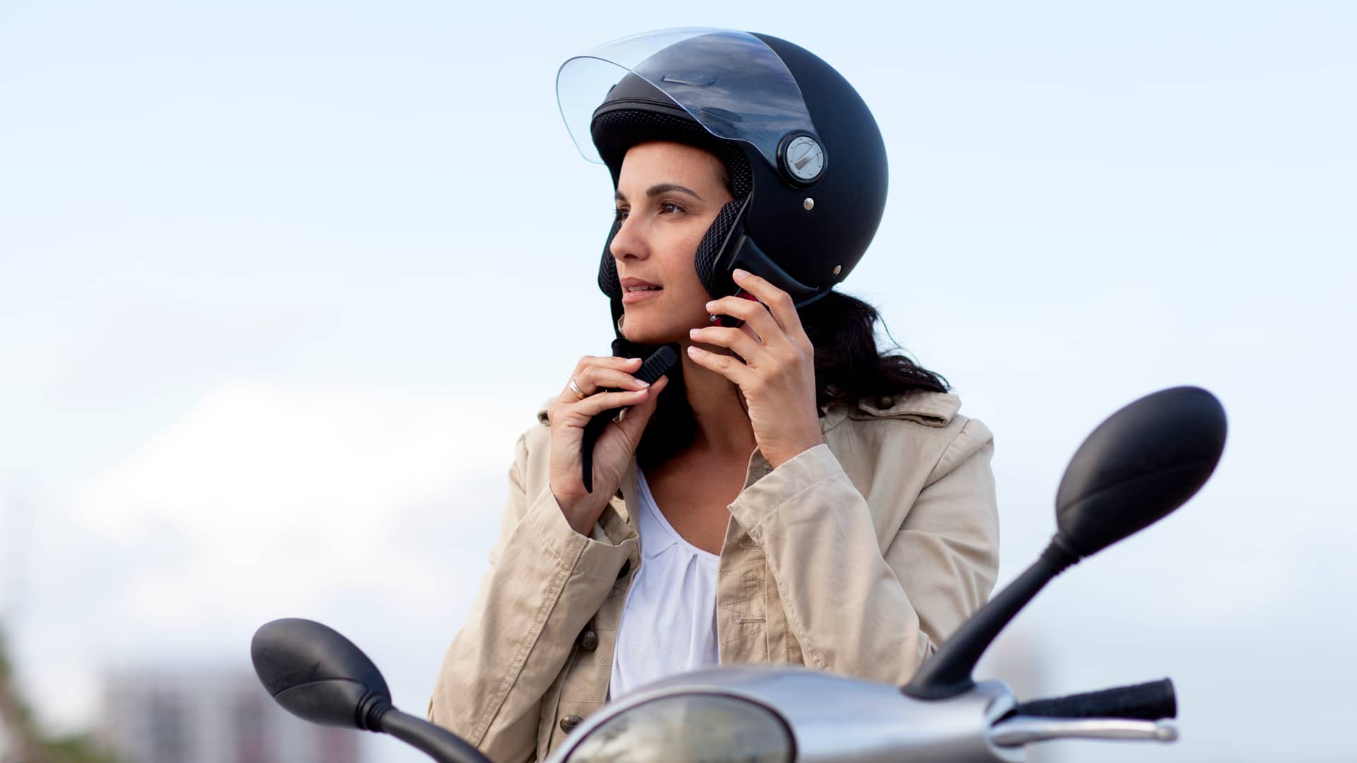 Mujer colocandose el casco para conducir su moto asegurada con qualitas Mujer colocandose el casco para conducir su moto asegurada con qualitas