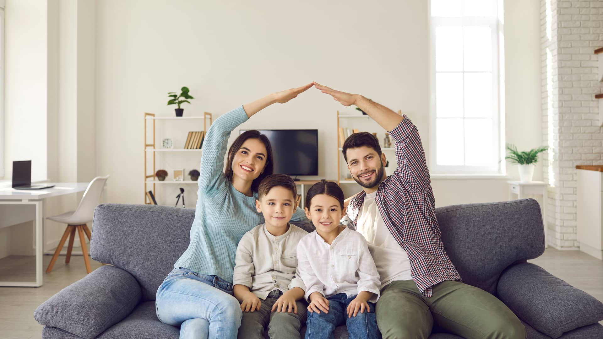 familia en el sofa de su casa protegiendose con los brazos que representa el seguro de hogar de reale seguros