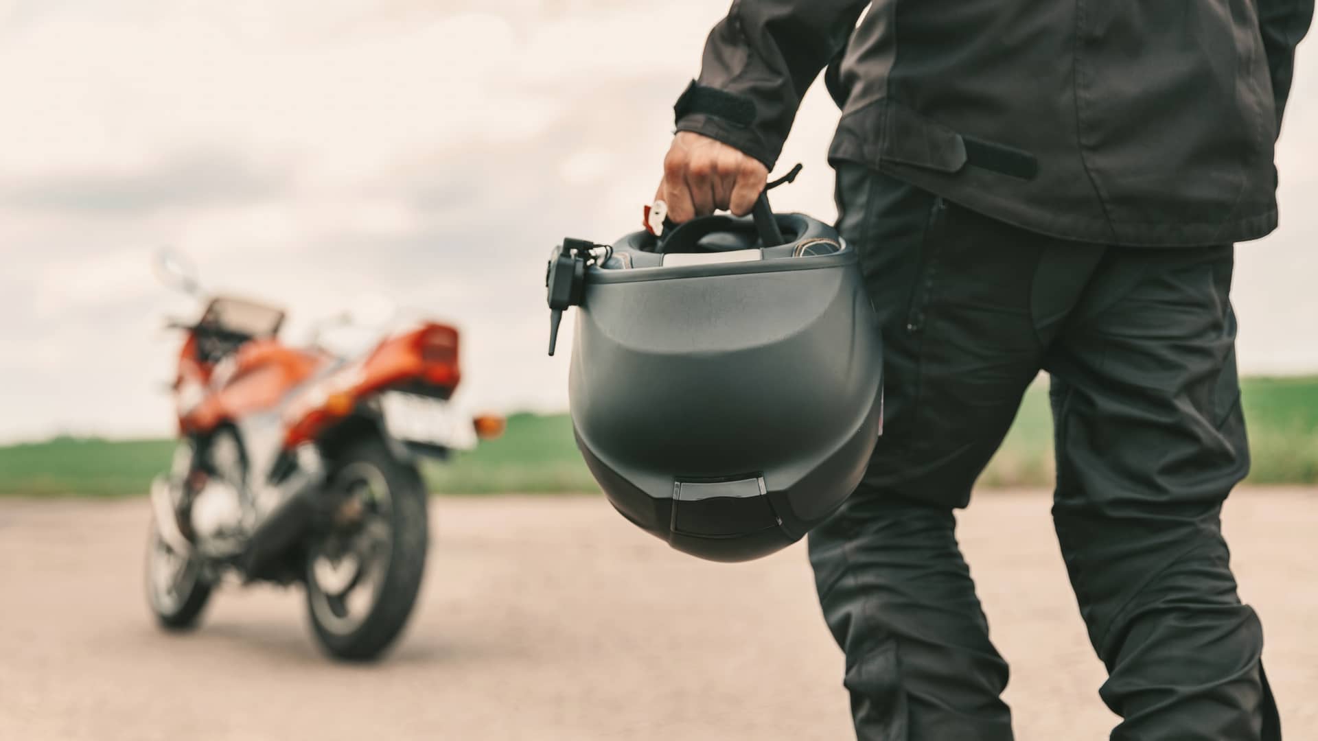 joven andando hacia su moto con un seguro epecial de reale con el casco en la mano joven andando hacia su moto con un seguro epecial de reale con el casco en la mano