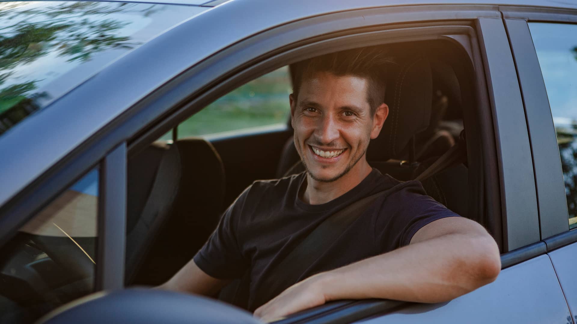 Hombre sonriente conduciendo su coche asegurado con regal