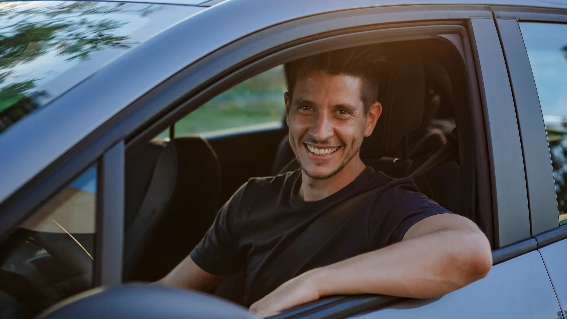 Hombre sonriente conduciendo su coche asegurado con regal Hombre sonriente conduciendo su coche asegurado con regal