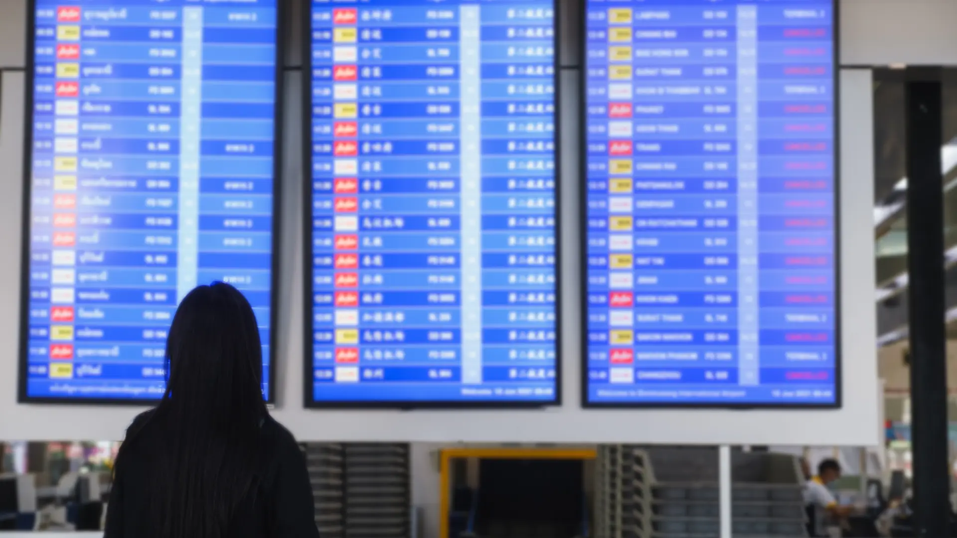 Una turista mirando las pantallas de un aeropuerto bien informada por el área de clientes de Sanitas Una turista mirando las pantallas de un aeropuerto bien informada por el área de clientes de Sanitas
