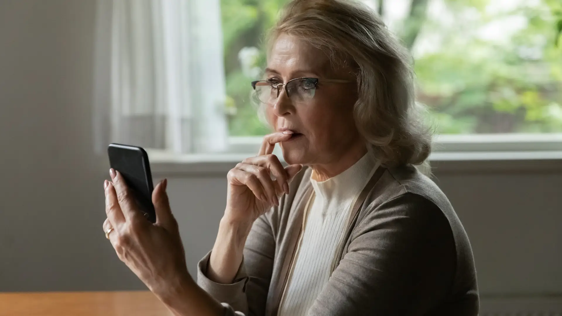 Mujer de avanzada edad solicitando con su teléfono móvil una autorización en Sanitas Mujer de avanzada edad solicitando con su teléfono móvil una autorización en Sanitas