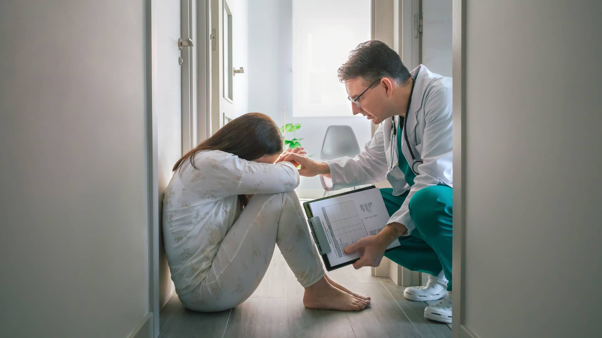 Psiquiatra del cuadro médico de Sanitas atentiendo a una joven sentada en el suelo