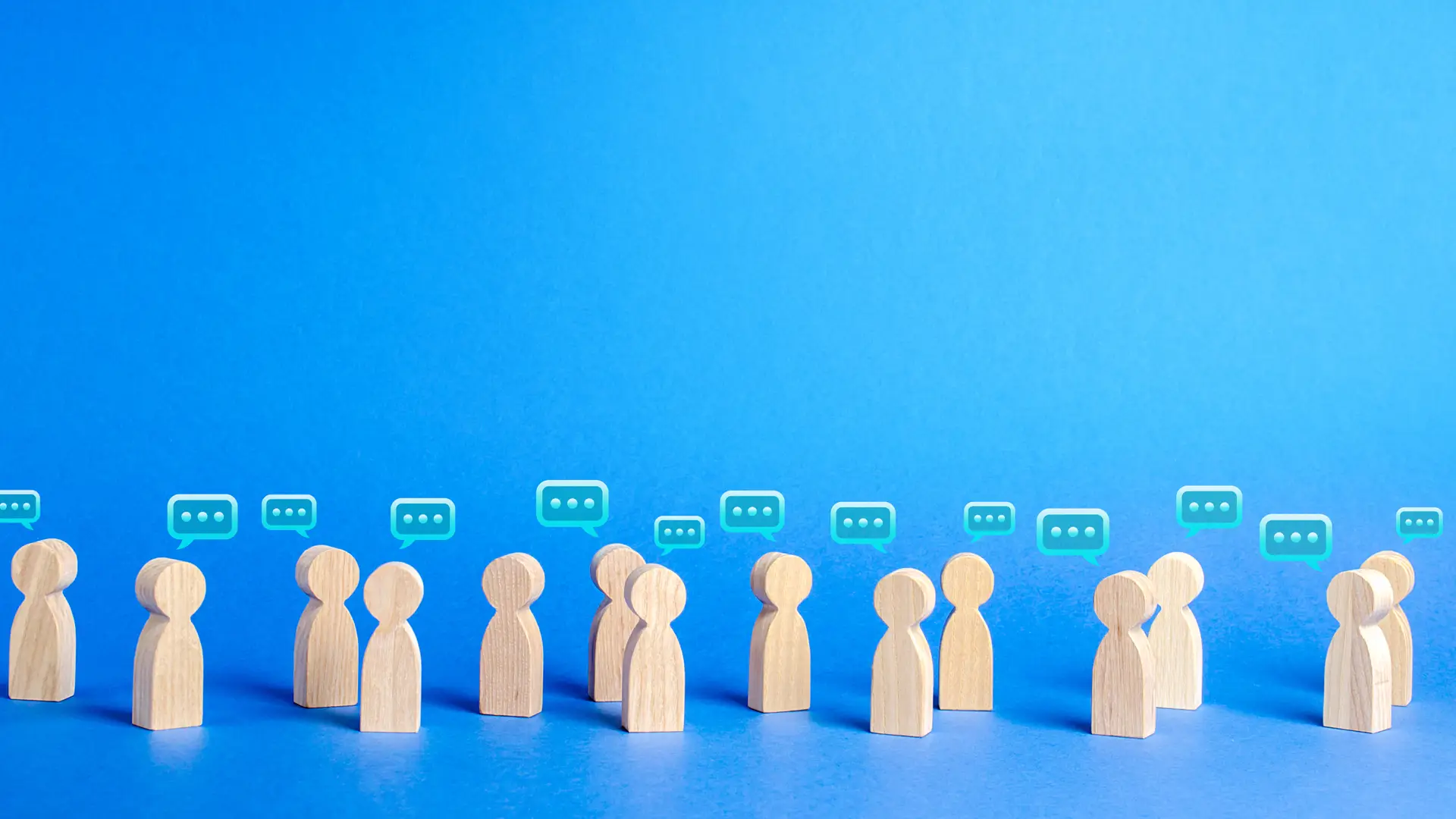 Figuras de personas de madera con bocadillos de papel donde dan sus opiniones sobre los seguros de Sanitas