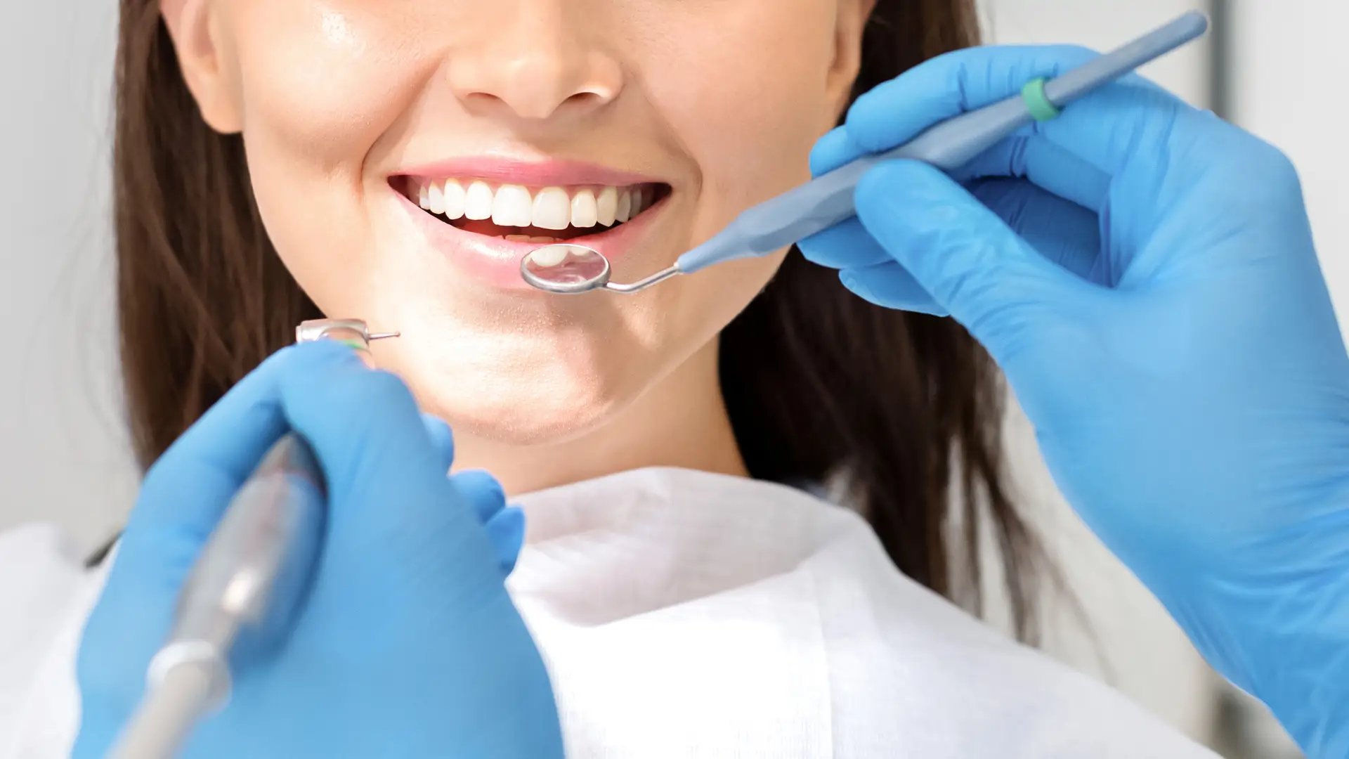 Chica joven sonriendo con los intrumentos del dentista cerca porque tiene el seguro dental 21 de Sanitas 