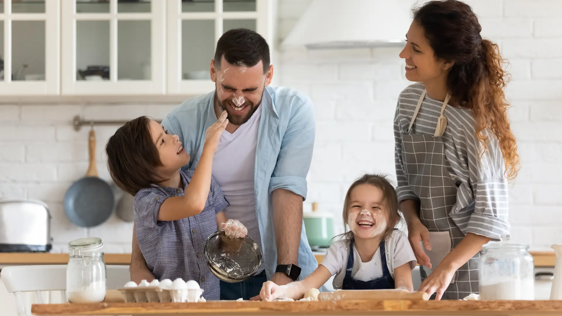 Una familia contenta cocinando en casa tranquilos porque tienen un seguro de hogar de Sanitas Una familia contenta cocinando en casa tranquilos porque tienen un seguro de hogar de Sanitas