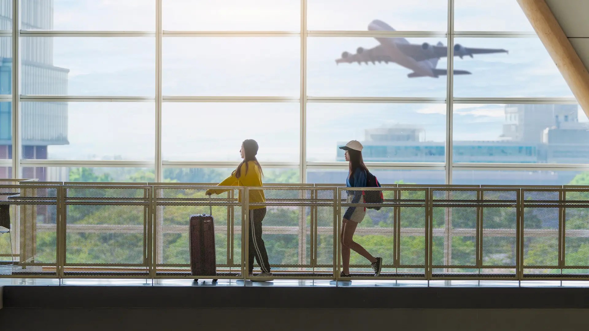 Dos turistas de viaje en un aeropuerto relajadas porque llevan todo cerrado con su seguro de viajes de Sanitas Dos turistas de viaje en un aeropuerto relajadas porque llevan todo cerrado con su seguro de viajes de Sanitas