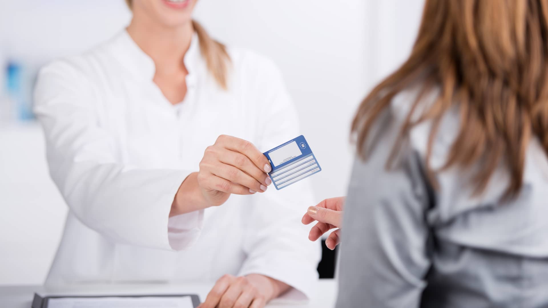 Una médico de Sanitas entregándole la tarjeta de salud a una paciente