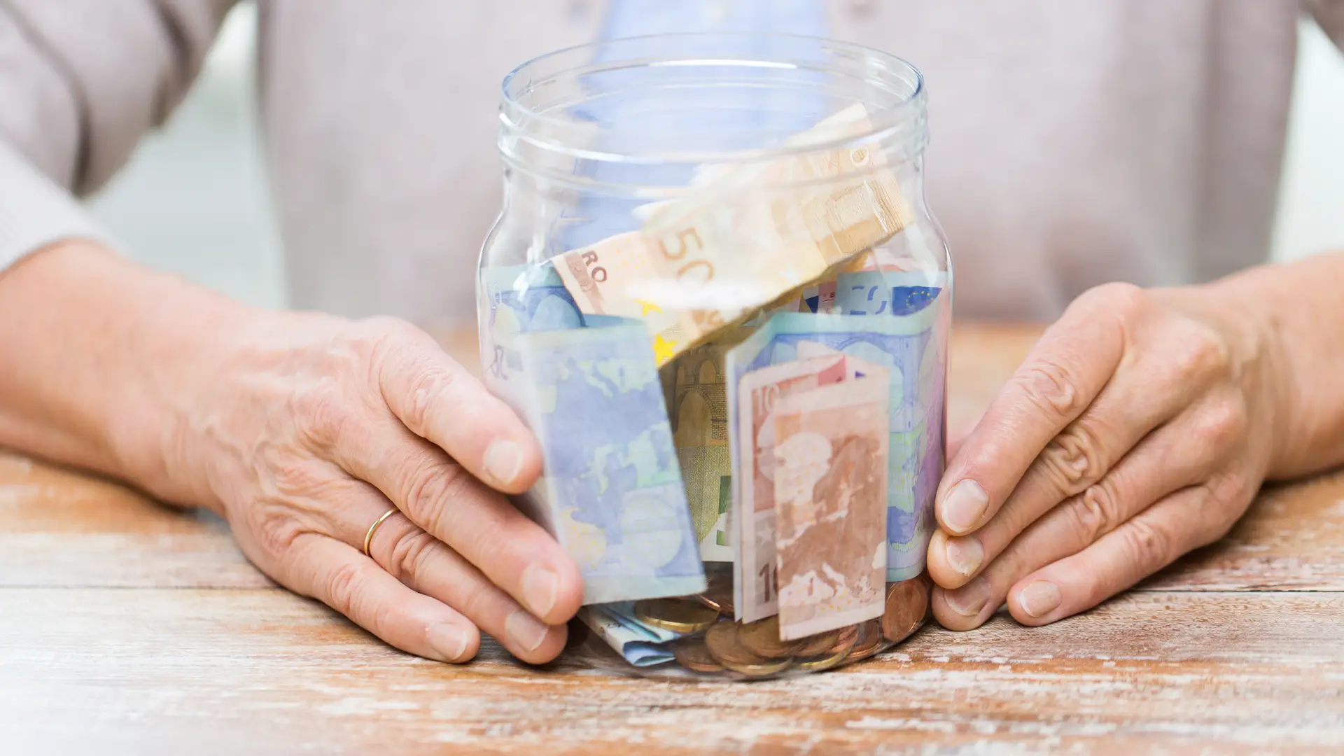 Persona con bote de monedas representa beneficios generados en el fondo de inversión unit linked de seguros santalucia Persona con bote de monedas representa beneficios generados en el fondo de inversión unit linked de seguros santalucia