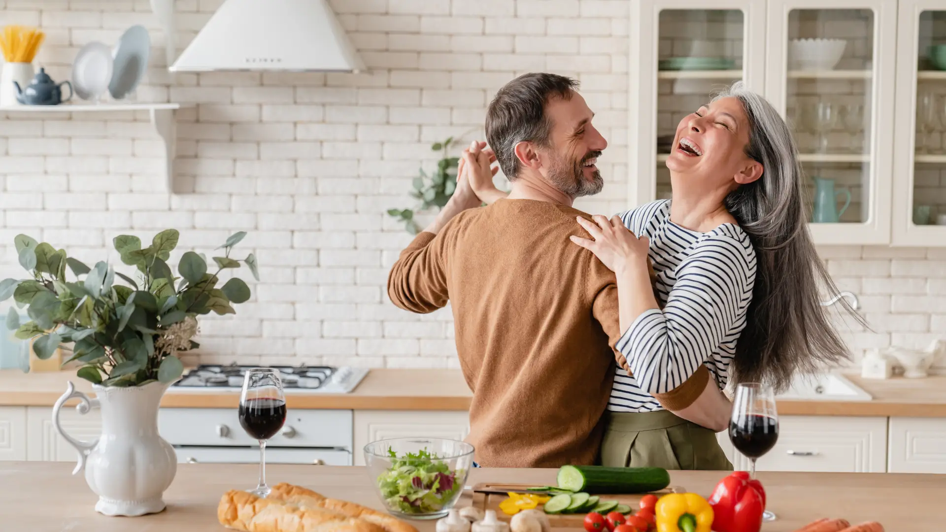 Pareja baila en su cocina en una pausa de cocinar, sonrien porque estan protegidos por un seguro de hogar de Seguros Bilbao