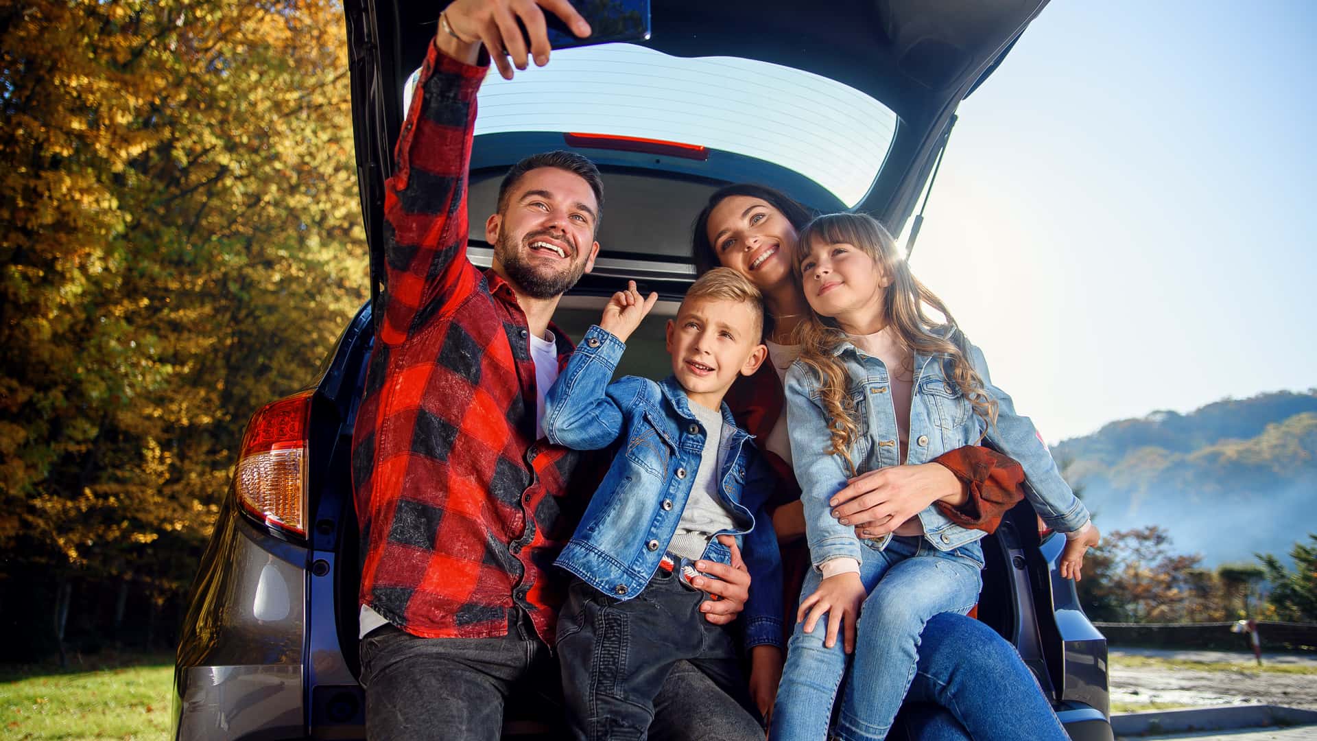 Familia sentada en el maletero de su coche asegurado con verti haciendose una foto Familia sentada en el maletero de su coche asegurado con verti haciendose una foto