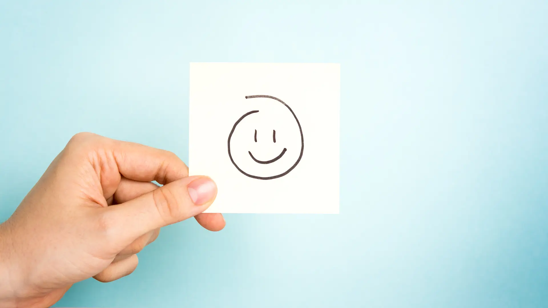 Mano con posit con cara sonriente para dar opinión sobre aseguradora zurich Mano con posit con cara sonriente para dar opinión sobre aseguradora zurich