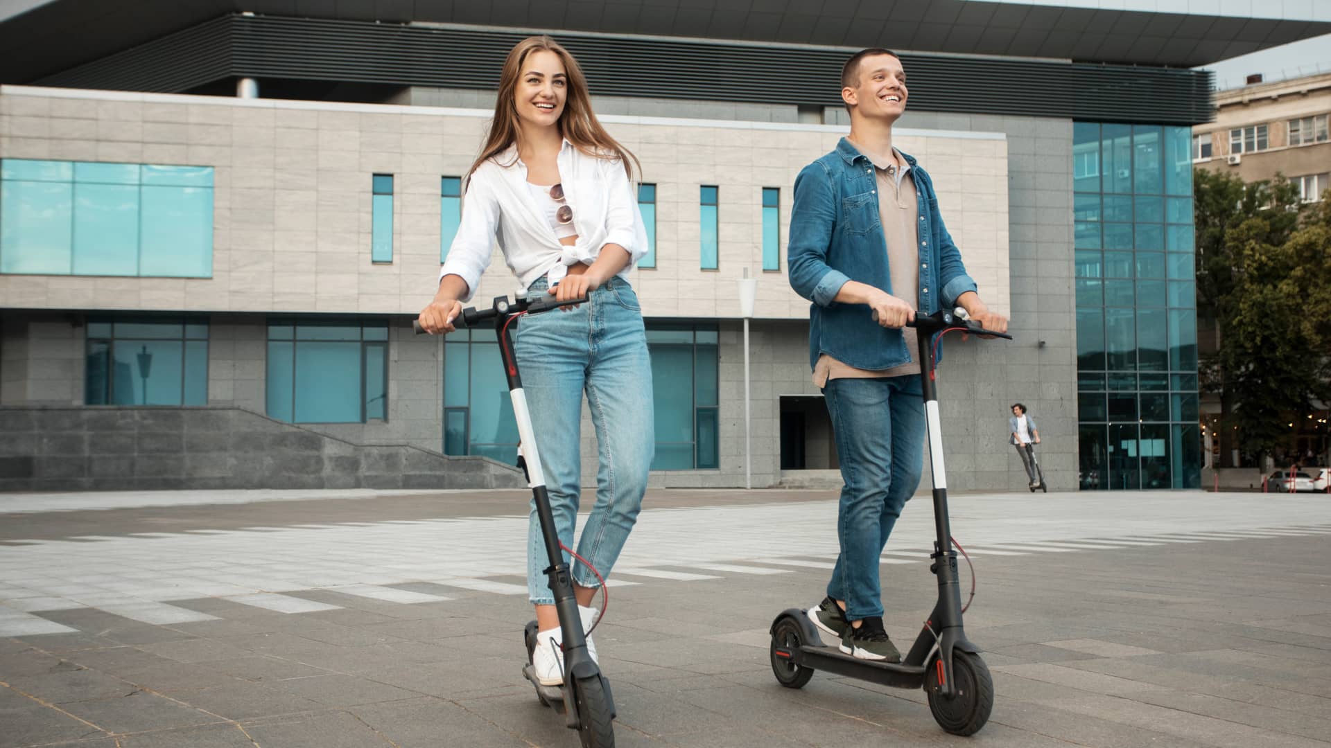 Amigos circulando por ciudad con sus patinetes eléctricos asegurados con zurich Amigos circulando por ciudad con sus patinetes eléctricos asegurados con zurich