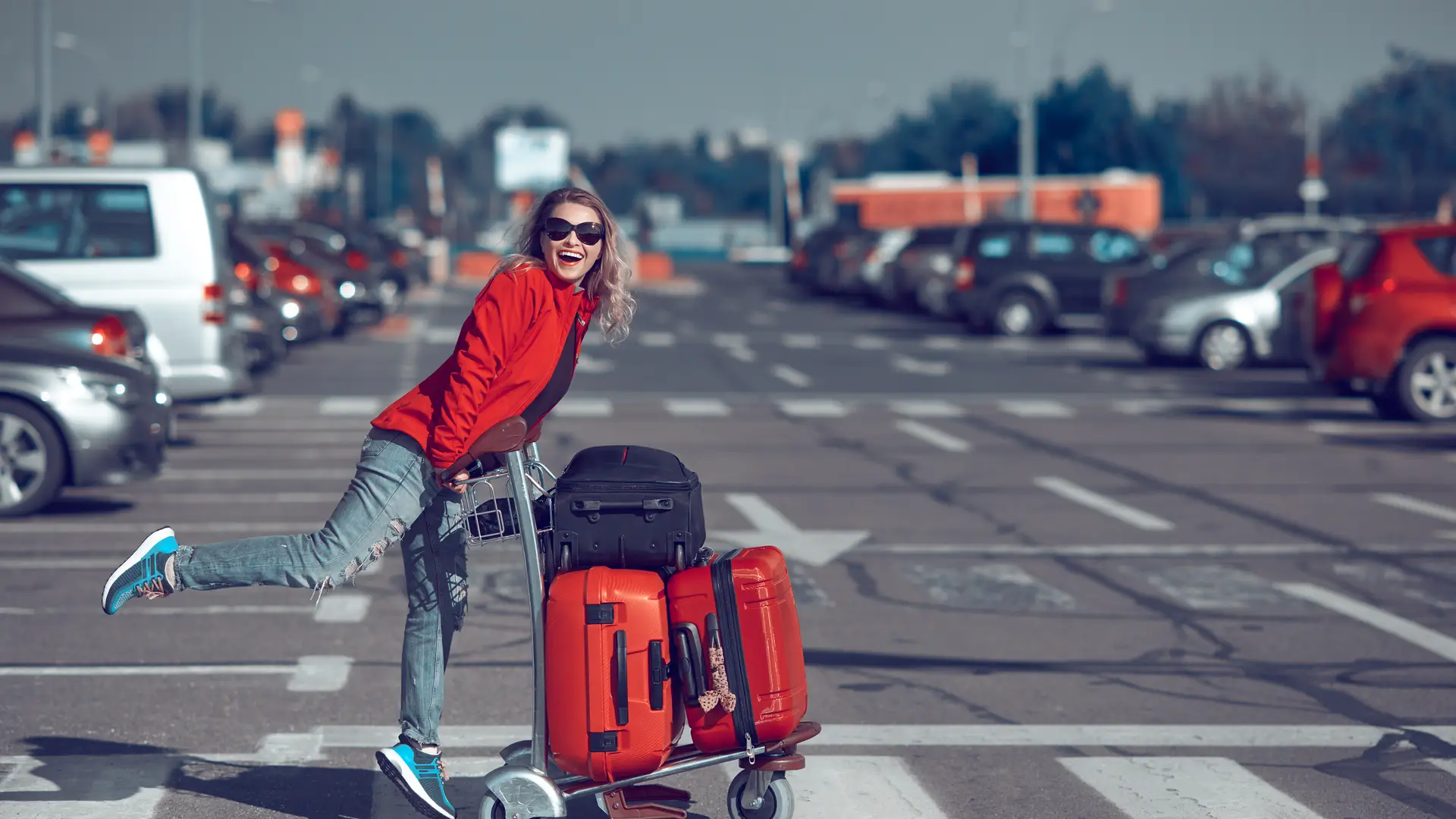 Mujer alegre empujando carro con maletas para irse de vacaciones para tomar su vuelo con la tranquilidad que le da saber que tiene un seguro de viaje con zurich Mujer alegre empujando carro con maletas para irse de vacaciones para tomar su vuelo con la tranquilidad que le da saber que tiene un seguro de viaje con zurich
