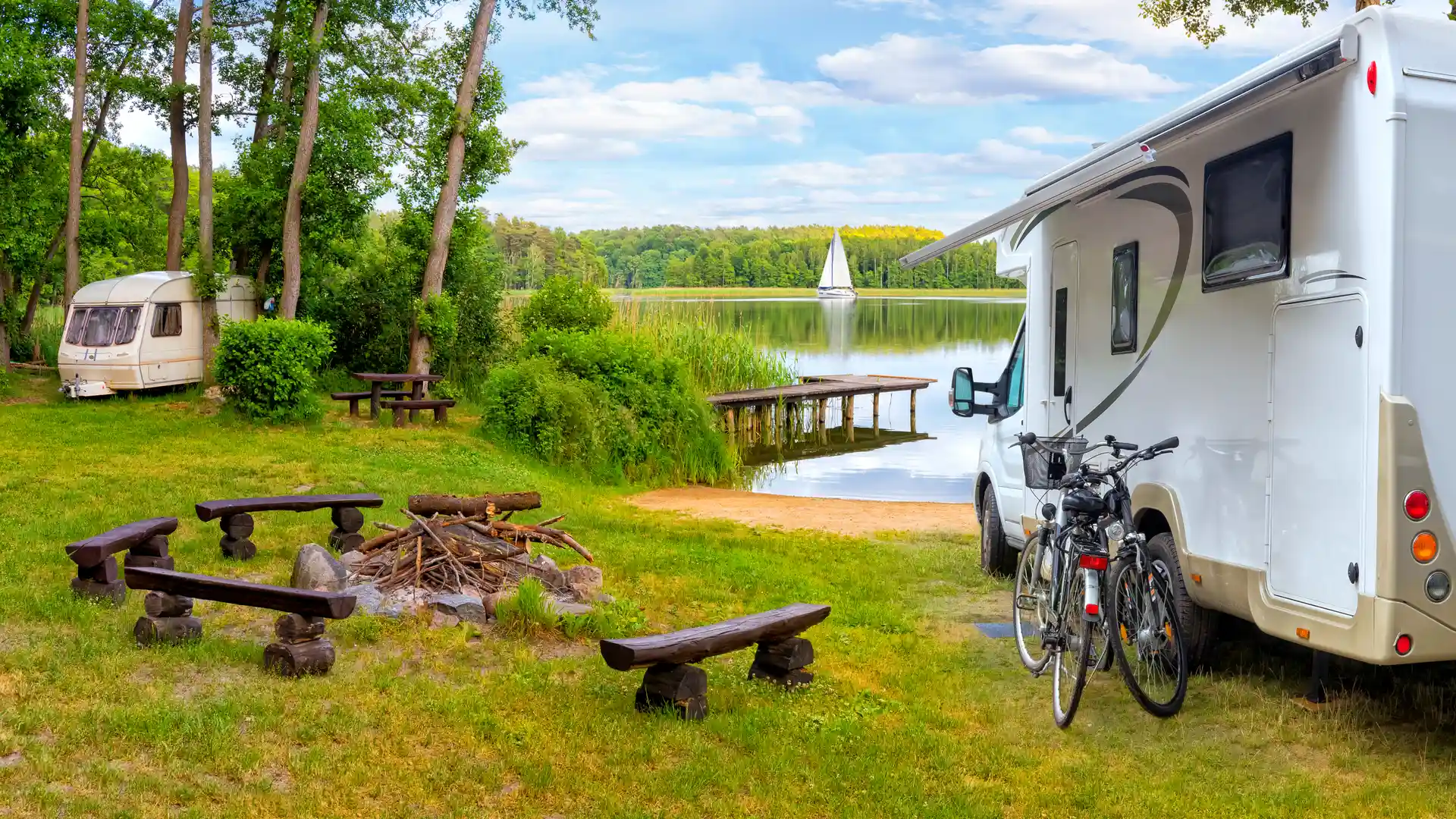 Pareja de vacaciones junto a un lago con sus bicis y con autocaravana alquilada