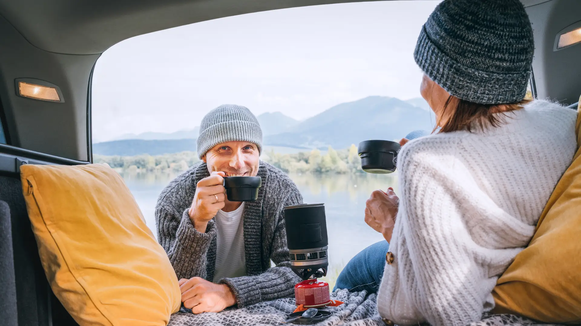 Pareja sonriente tomando un café simboliza la opinión y grado de satisfacción con el seguro de autocaravana Pareja sonriente tomando un café simboliza la opinión y grado de satisfacción con el seguro de autocaravana