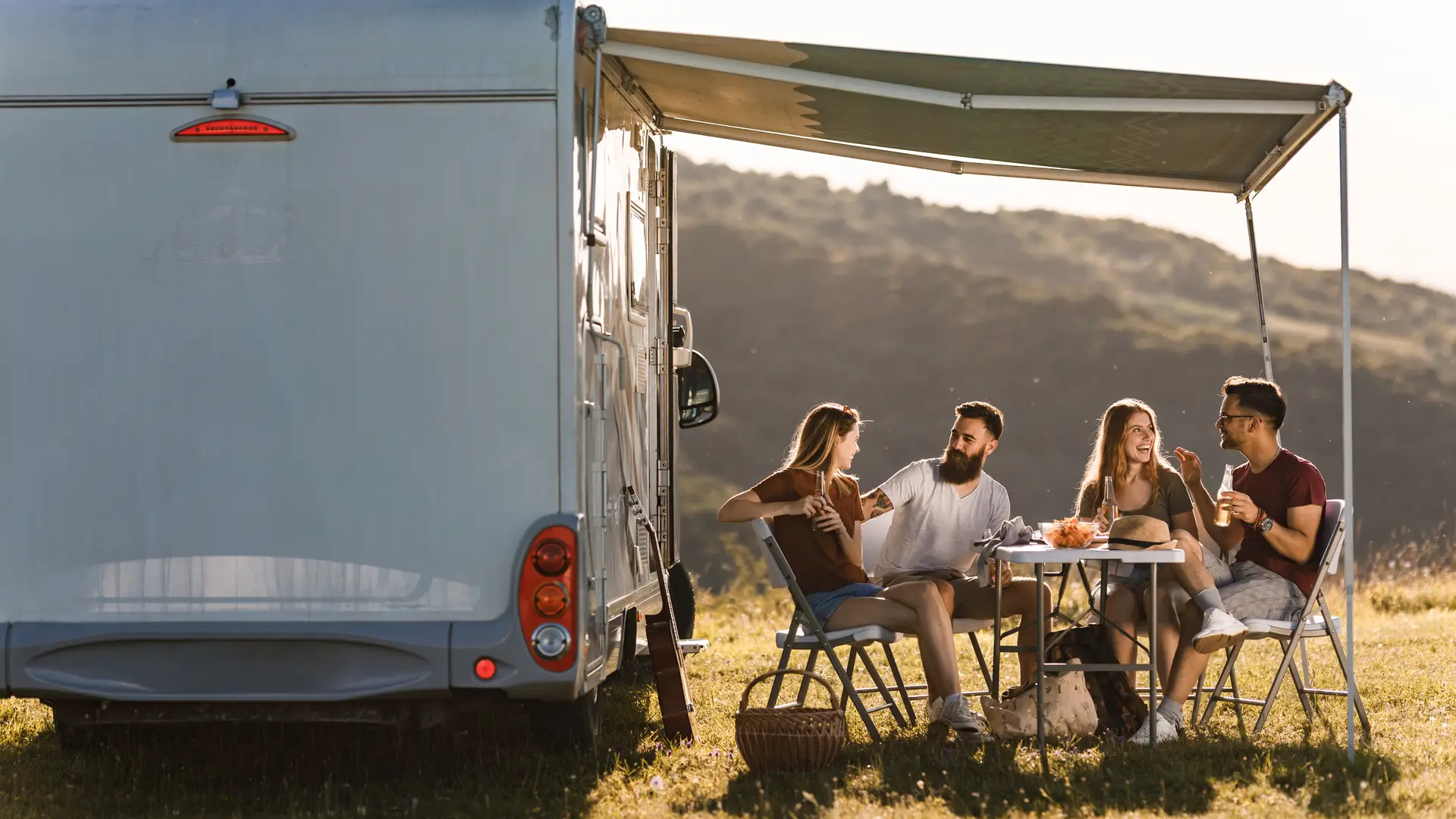 Amigos merendando junto a autocaravana la cual han alquilado por días al igual que han hecho un seguro por días Amigos merendando junto a autocaravana la cual han alquilado por días al igual que han hecho un seguro por días