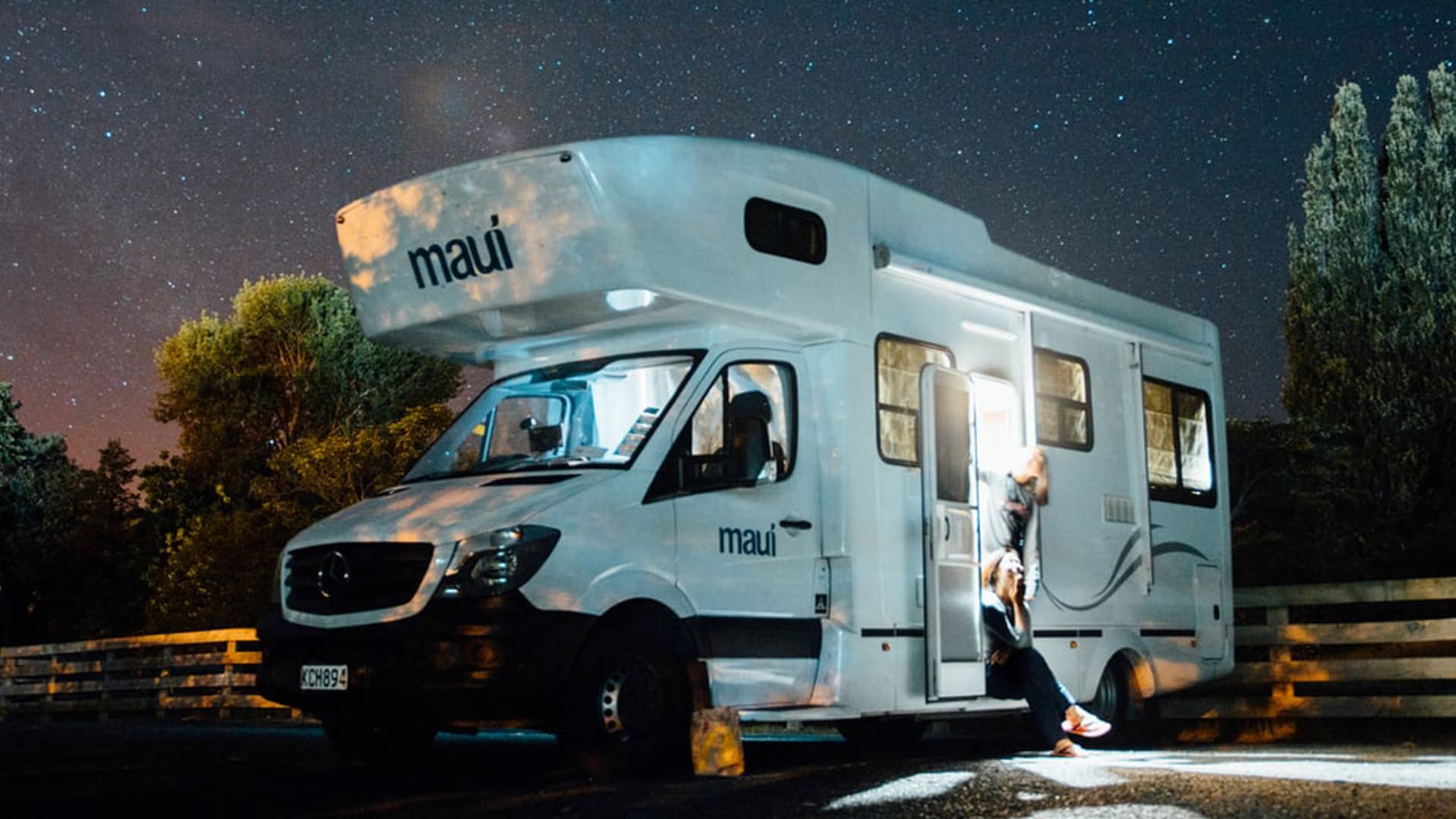 Pareja tumbada en cama de autocaravana con vistas hacia el mar con la tranquilidad que les da tener un seguro