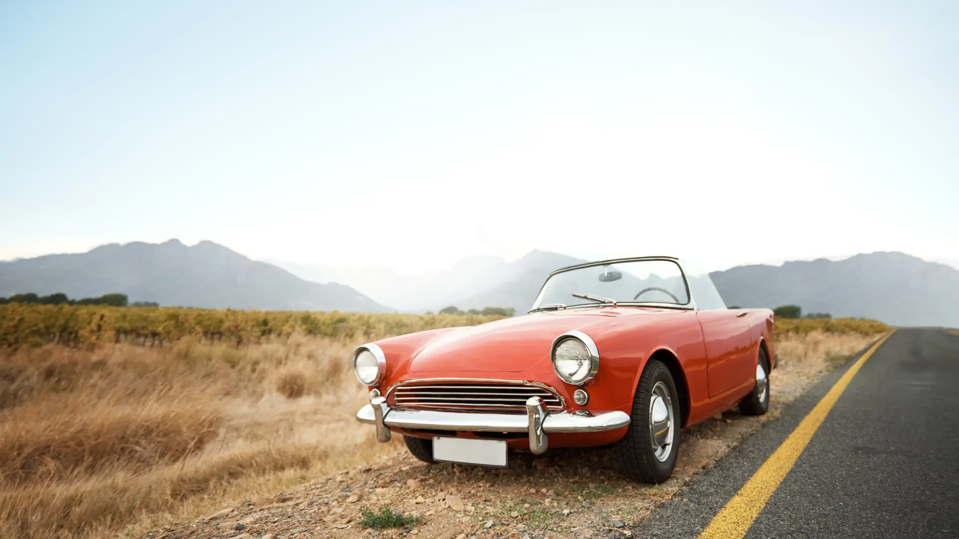 Coche antiguo con seguro para coches clásicos estacionado junto a carretera en obras Coche antiguo con seguro para coches clásicos estacionado junto a carretera en obras