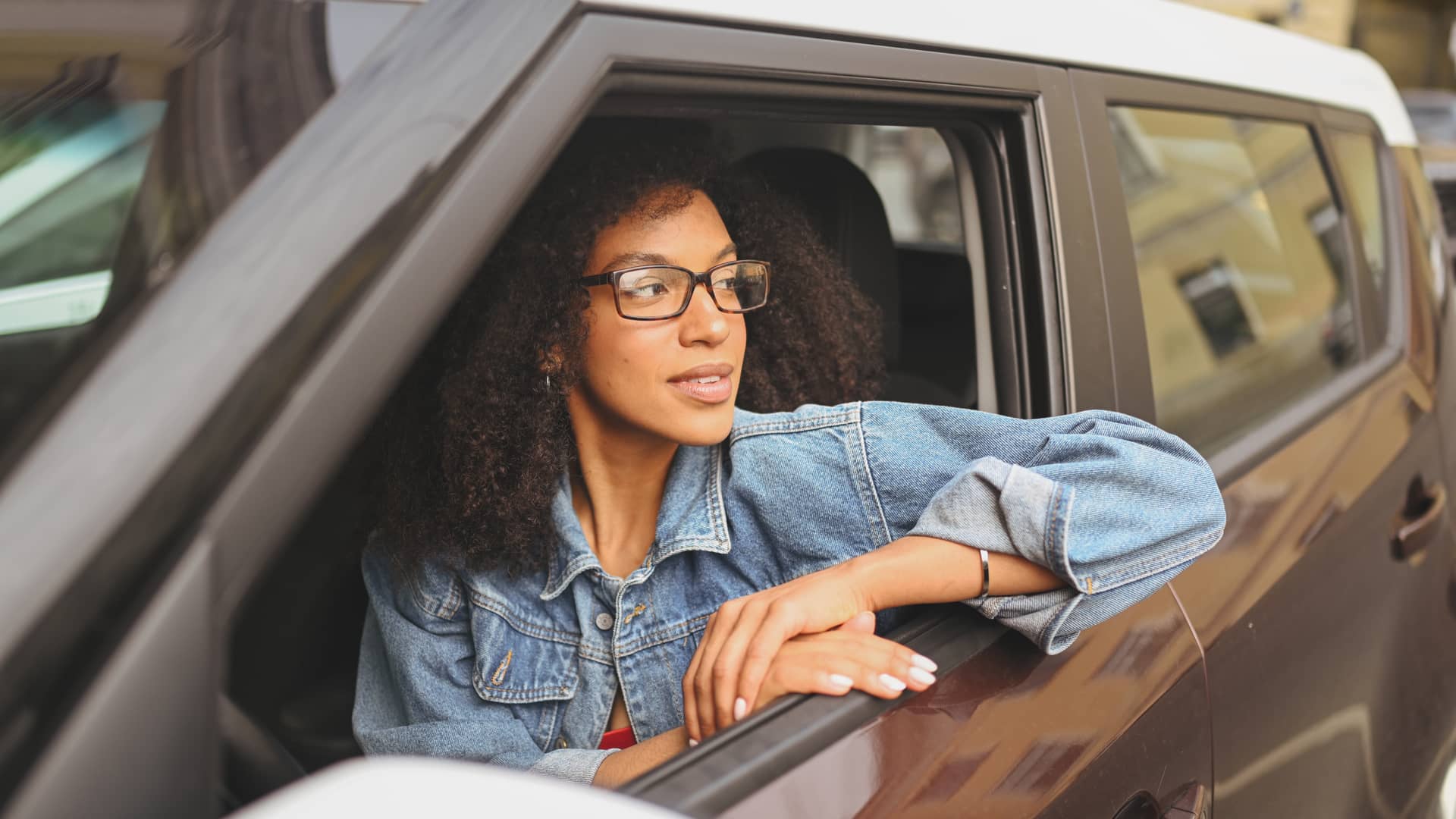 Joven mirando por la ventanilla sentada en su coche sín carnet