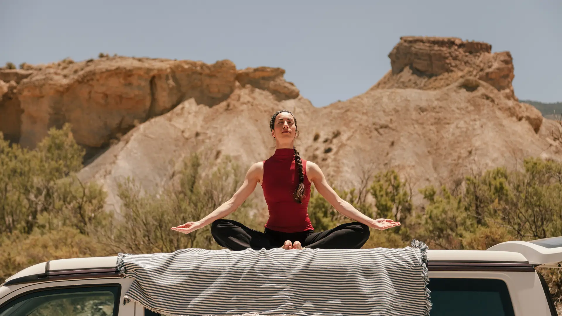 Mujer practicando yoga en el techo de una furgoneta en el desierto tras conseguir dar de baja seguro Mujer practicando yoga en el techo de una furgoneta en el desierto tras conseguir dar de baja seguro