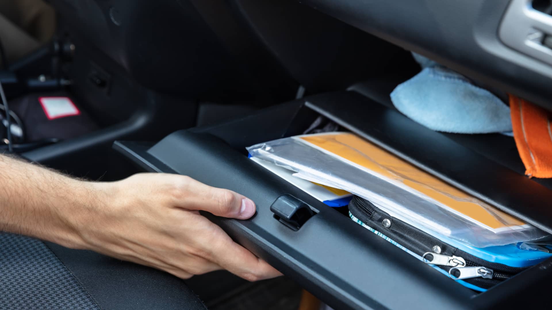 Hombre buscando en la guantera los papeles de su coche entre los que se encuentra el historial de siniestralidad Hombre buscando en la guantera los papeles de su coche entre los que se encuentra el historial de siniestralidad