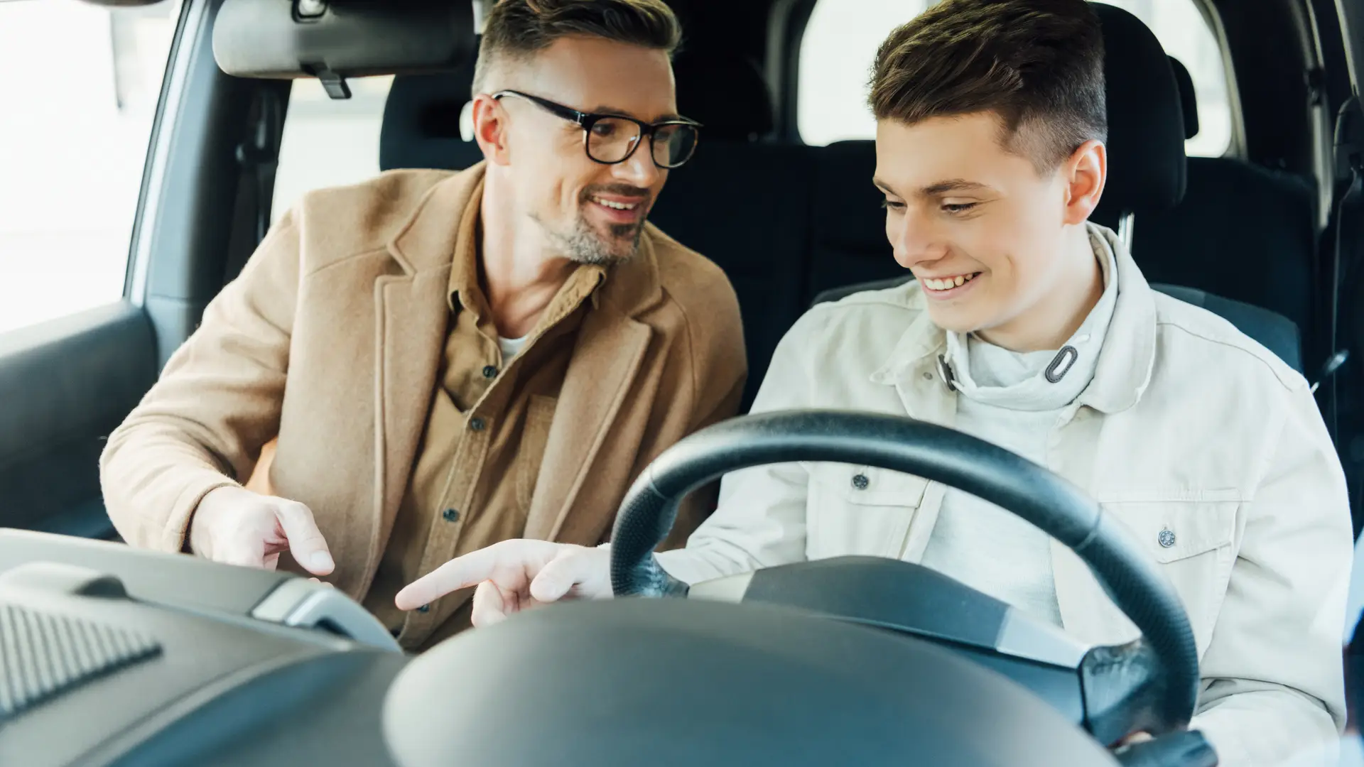 Un padre con su hijo conduciendo porque ha conseguido meterlo en su seguro de coche Un padre con su hijo conduciendo porque ha conseguido meterlo en su seguro de coche