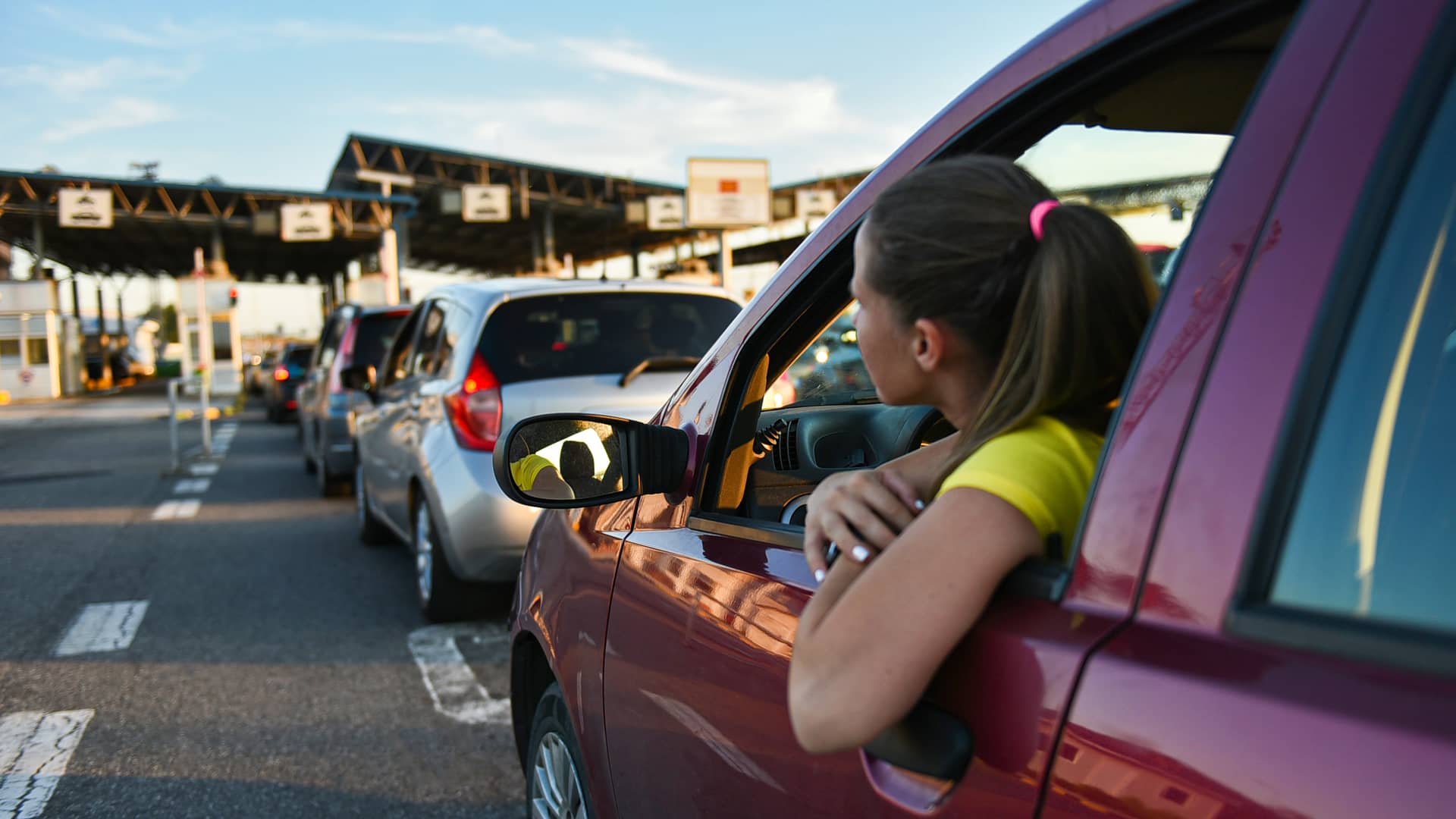 Mujer viajando al extranjero con su vehículo esperando para pasar peaje de frontera