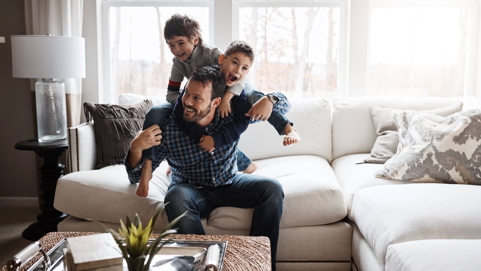 Padre jugando con hijos en el salón de su vivienda con seguro de hogar de todo el contenido de la casa Padre jugando con hijos en el salón de su vivienda con seguro de hogar de todo el contenido de la casa