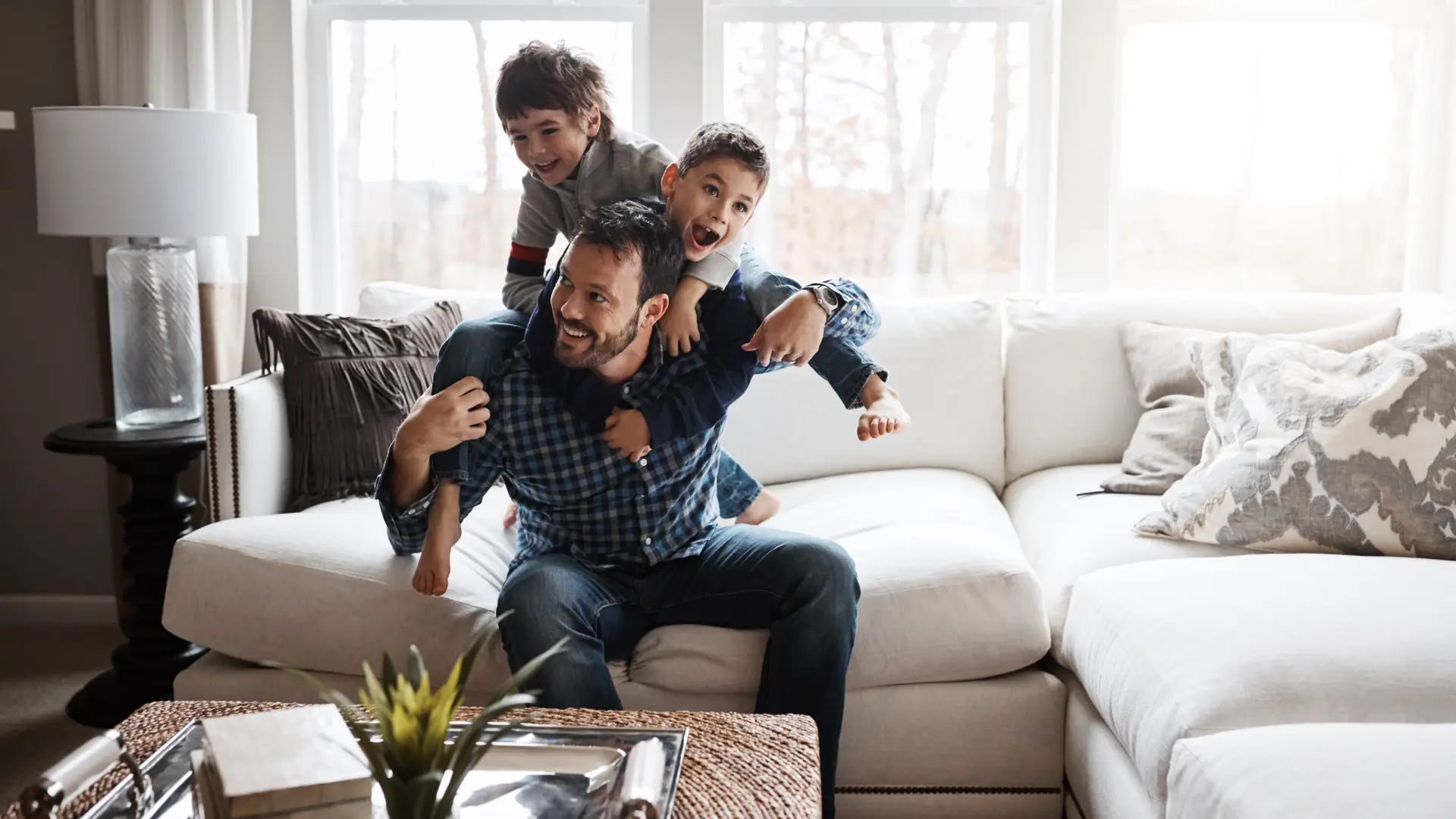 Padre jugando con hijos en el salón de su vivienda con seguro de hogar de todo el contenido de la casa Padre jugando con hijos en el salón de su vivienda con seguro de hogar de todo el contenido de la casa