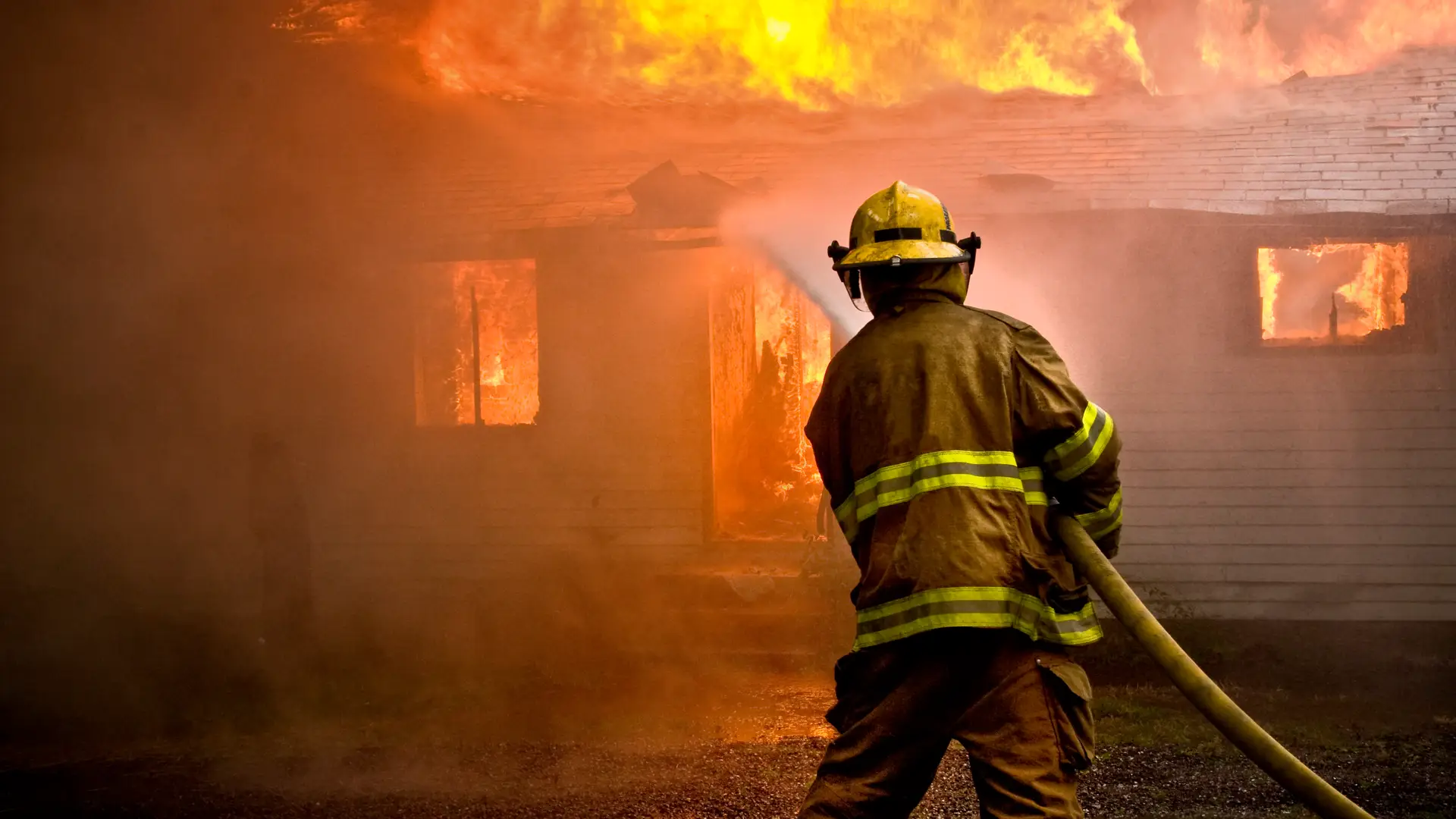 Bombero sofocando incendio en hogar con seguro de incendio Bombero sofocando incendio en hogar con seguro de incendio