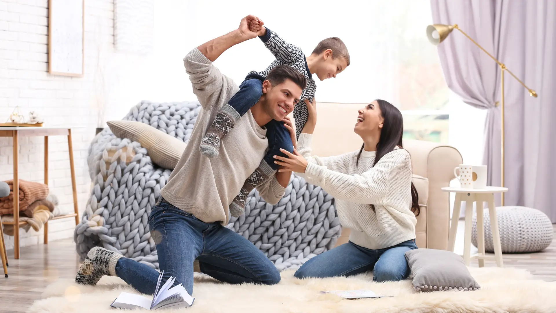 Una familia feliz jugando en casa tranquilos porque tienen un seguro a todo riesgo para su hogar