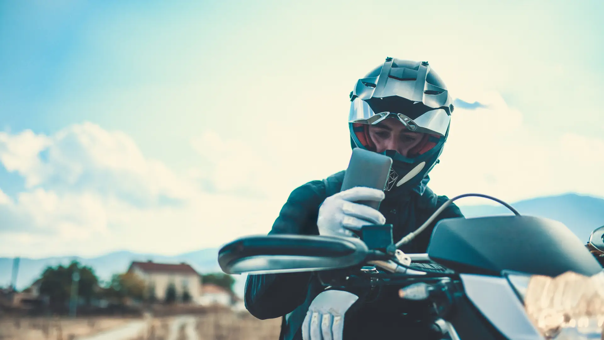Hombre haciendo un descanso con su moto de 200cc con seguro para echar un vistazo a su smartphone Hombre haciendo un descanso con su moto de 200cc con seguro para echar un vistazo a su smartphone