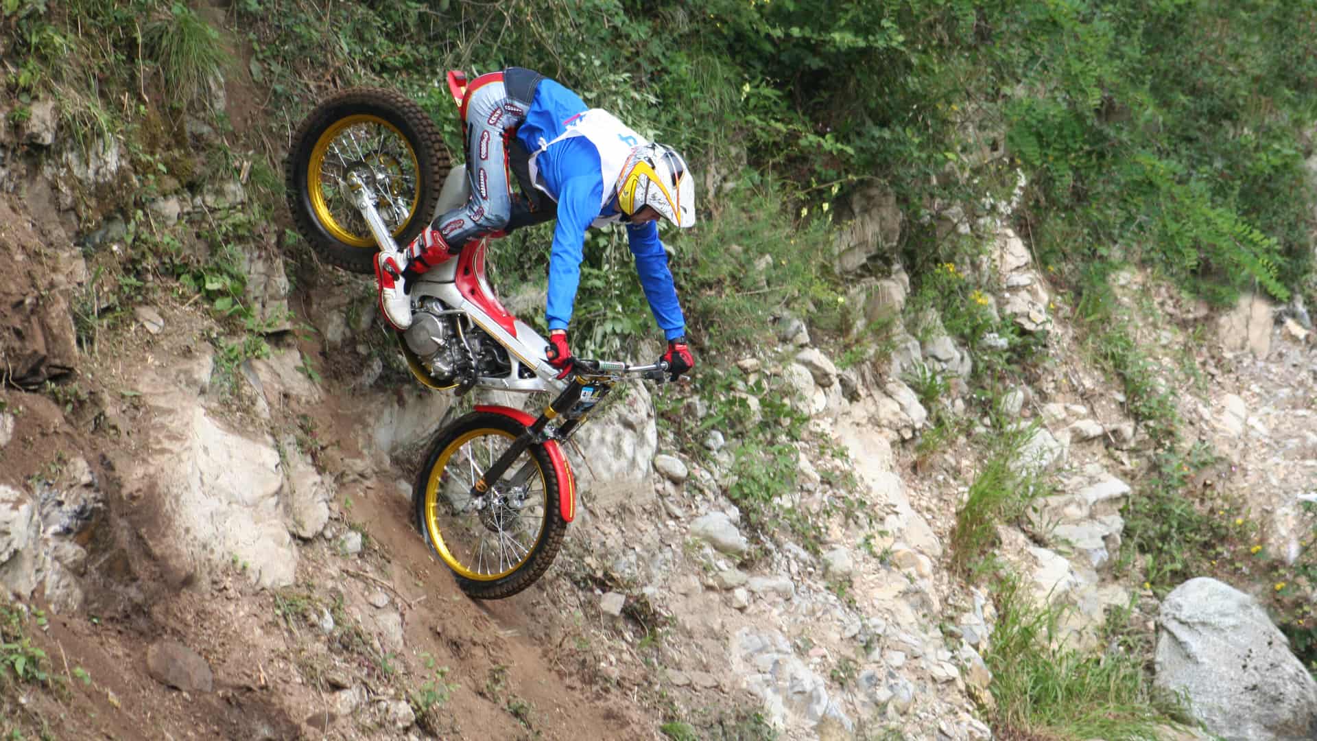 Joven descendiendo entre rocas con su moto de trial con seguro Joven descendiendo entre rocas con su moto de trial con seguro