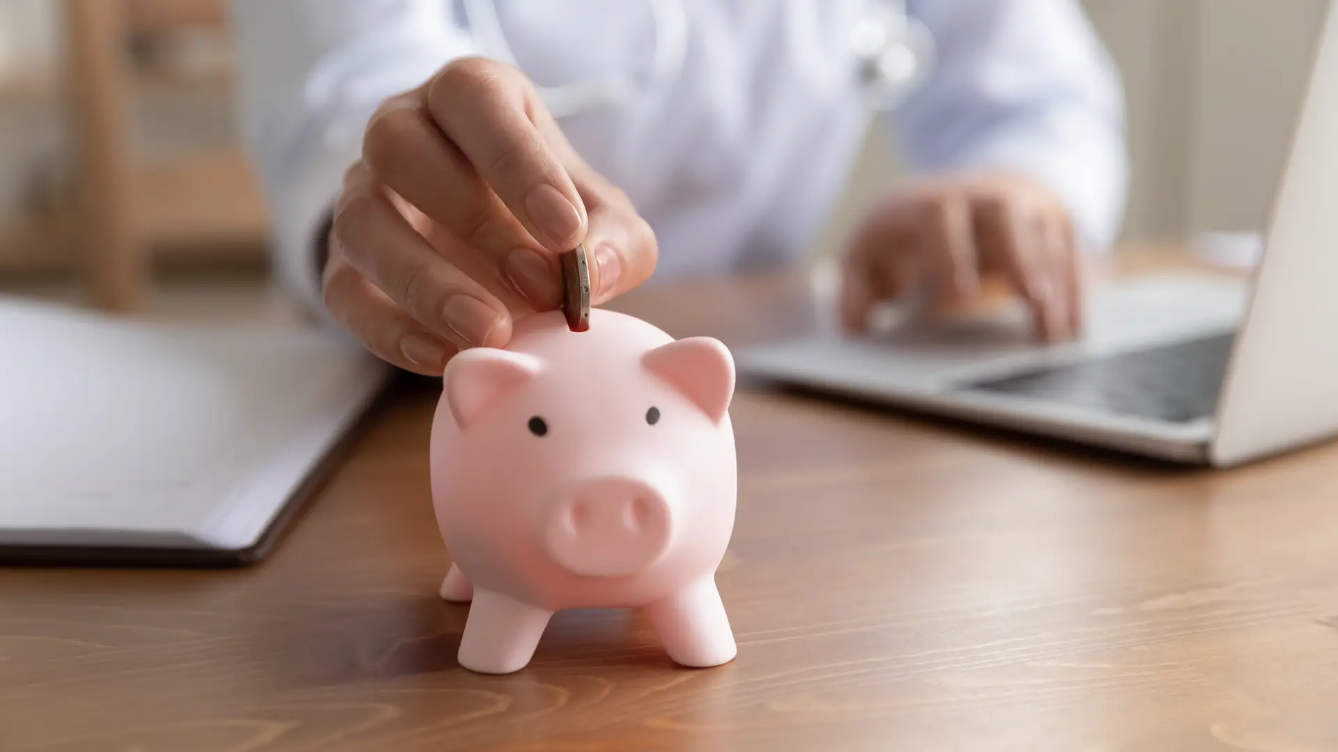 Una medico metiendo dinero en una hucha de cerdo para representar la retribucion flexible en los seguros de salud