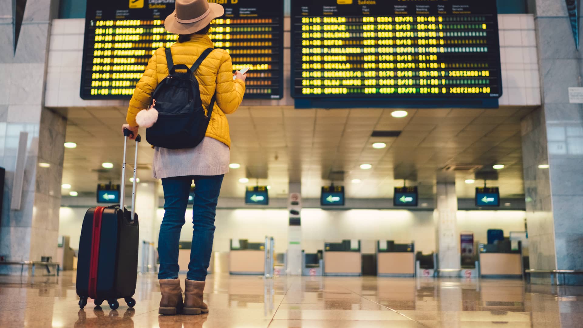 Mujer viendo que le han cancelado su vuelo y que no podra irse de viaje pero se encuentra tranquila porque tiene un seguro de cancelación y no perdera dinero con otras reservas Mujer viendo que le han cancelado su vuelo y que no podra irse de viaje pero se encuentra tranquila porque tiene un seguro de cancelación y no perdera dinero con otras reservas