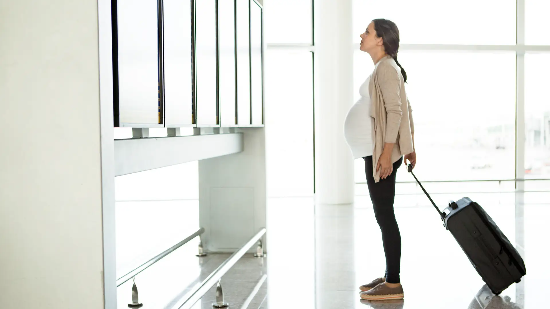 Mujer embarazada esperando su vuelo en el aeropuerto con seguro de viaje contratado Mujer embarazada esperando su vuelo en el aeropuerto con seguro de viaje contratado