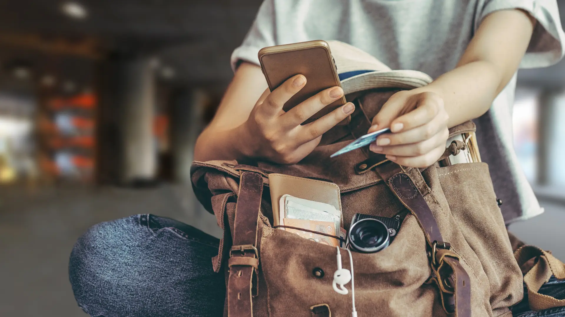 Joven de viaje realizando compra desde su smartphone con su tarjeta Joven de viaje realizando compra desde su smartphone con su tarjeta